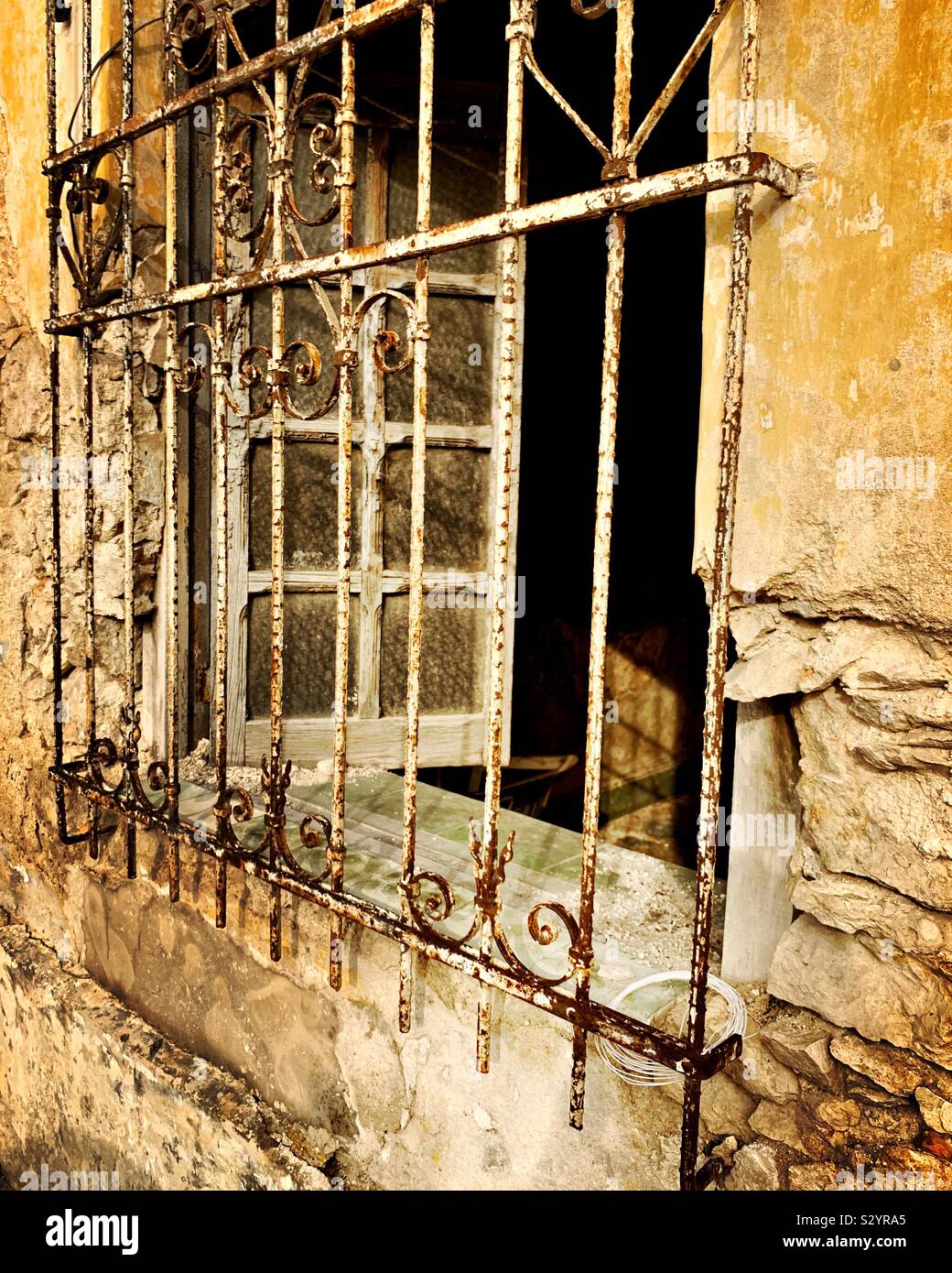 Un alterato e ferro forgiato coperchi della griglia di una finestra che si apre su un edificio di decadimento in Merida, Messico. Foto Stock