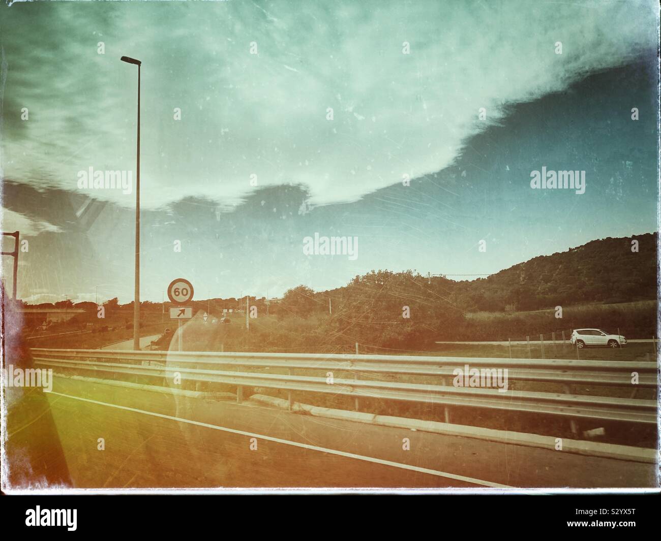 Vista posteriore del finestrino passeggero di un auto la guida su autostrada nel nord della Spagna con un grungy effetto retrò. Foto Stock