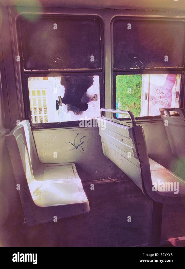 Vista delle sedi vuote nella parte posteriore di un autobus in movimento dall'interno a guardare gli edifici colorati in un giorno caldo in Progreso, México. Foto Stock