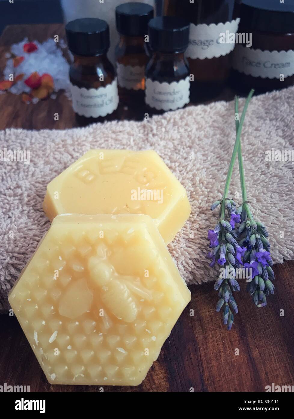 Cera d'api e lavanda con aromaterapia generico di bottiglie in background. Foto Stock