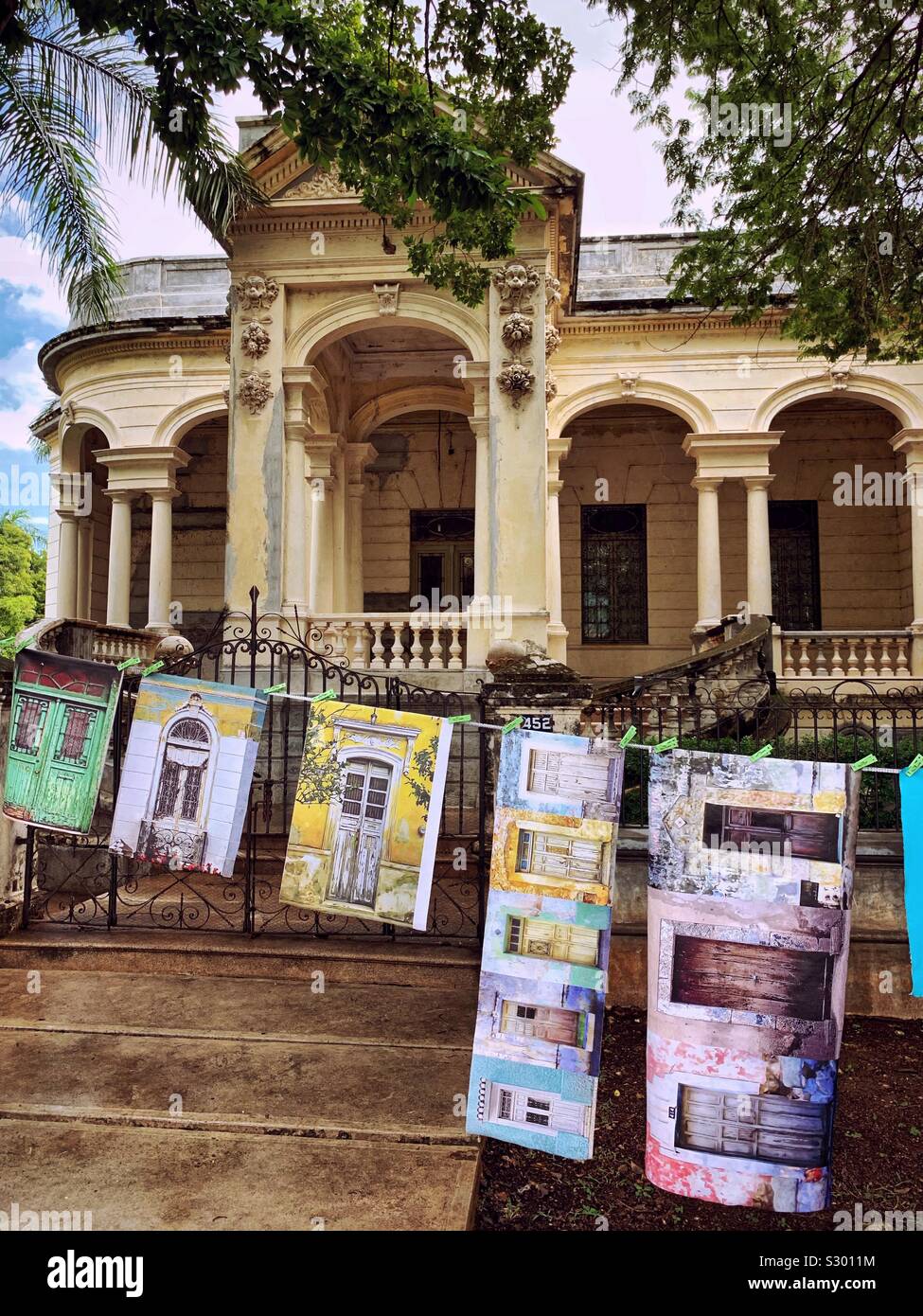 La domenica artwork è visualizzato sul Paseo de Montejo davanti a palazzi storici come questo che è stato restaurato al suo ex eleganza. Foto Stock