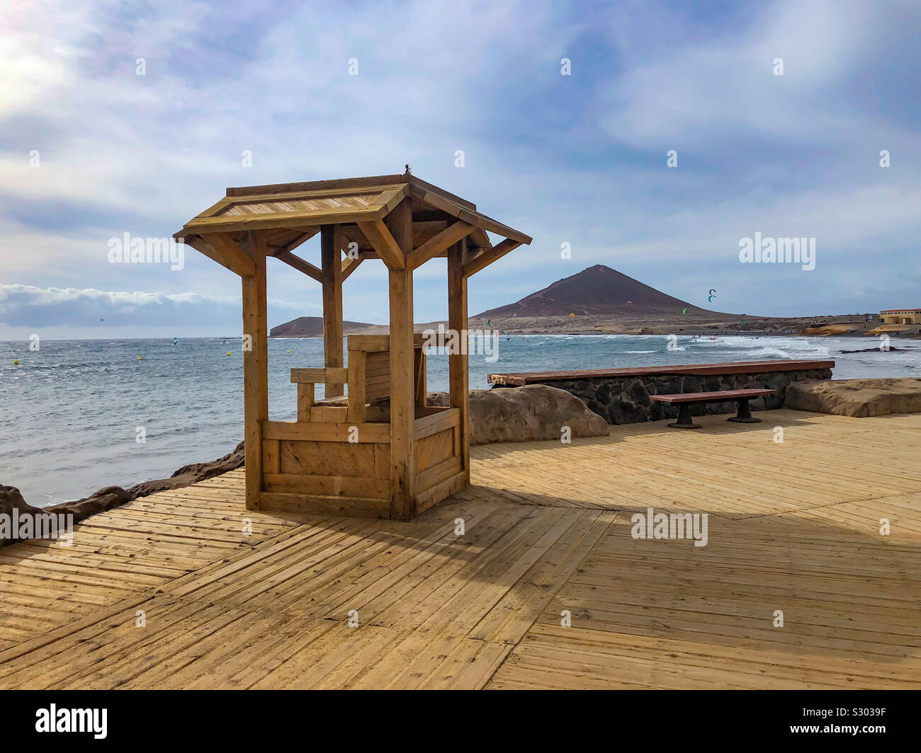 Strandpromenade in El Médano auf Teneriffa mit Blick auf den Rettungsturm, das Meer und die Berglandschaft im Hintergrund Foto Stock