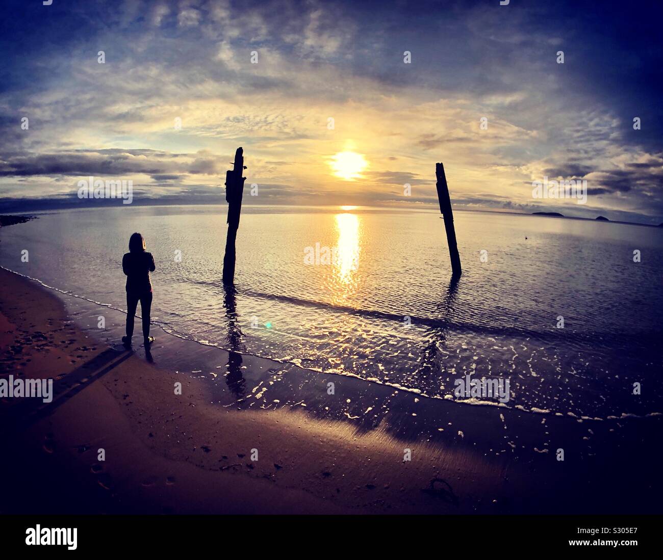 Donna di sunrise, Abersoch beach, Llanengan in Gwynedd, Galles Foto Stock