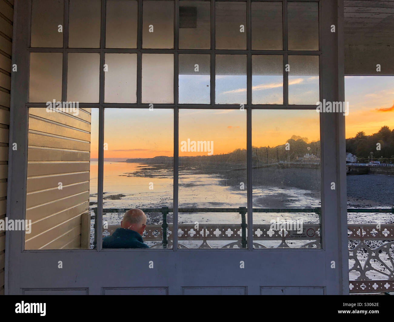Un gentleman godendo la vista su tutta Penarth spiaggia al tramonto da Penarth Pier. - Immagine stock catturata con smartphone