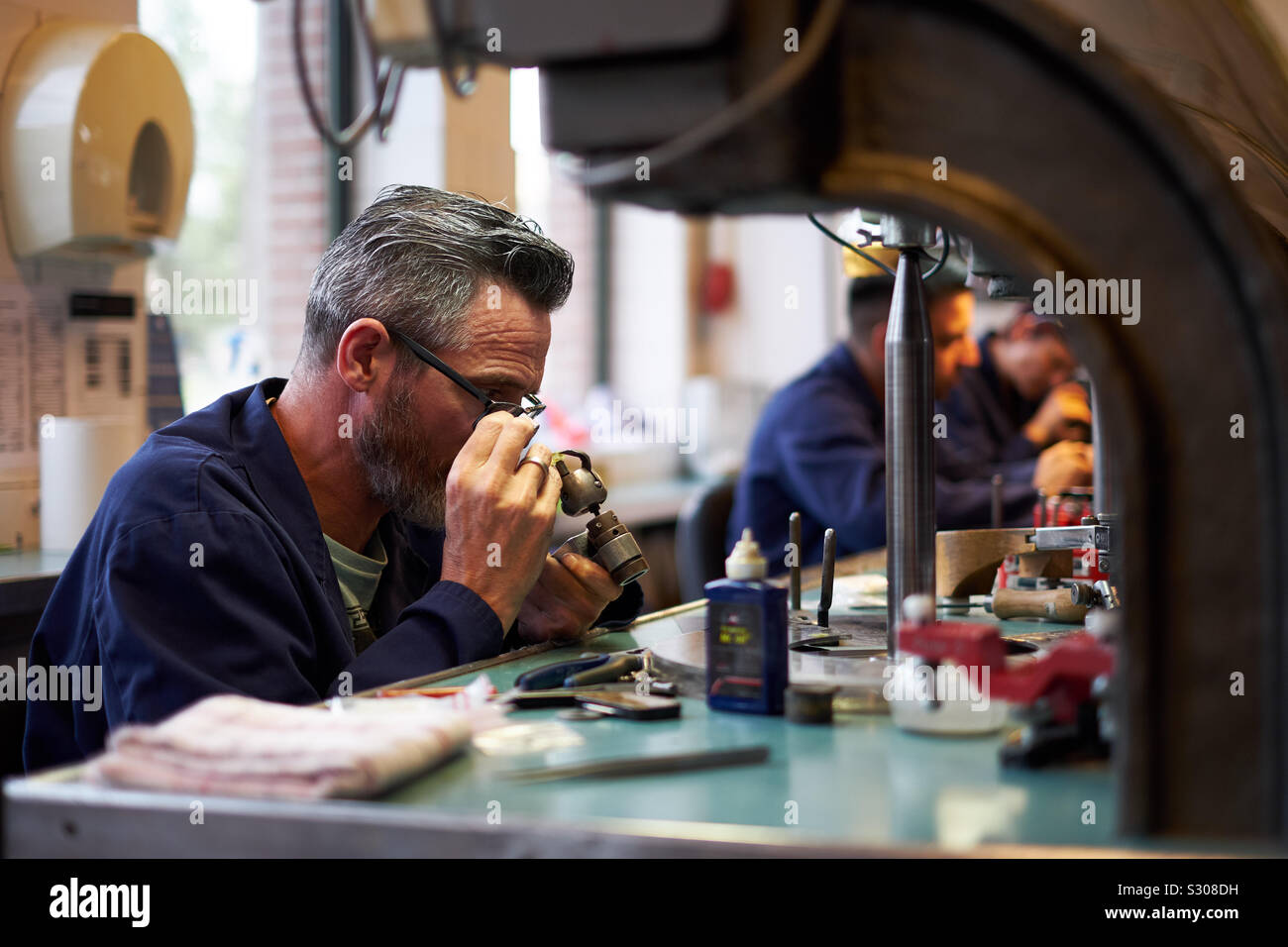 Un lavoratore esperto ispeziona un diamante durante il processo di taglio di diamanti Gassan in Amsterdam, Paesi Bassi. Foto Stock