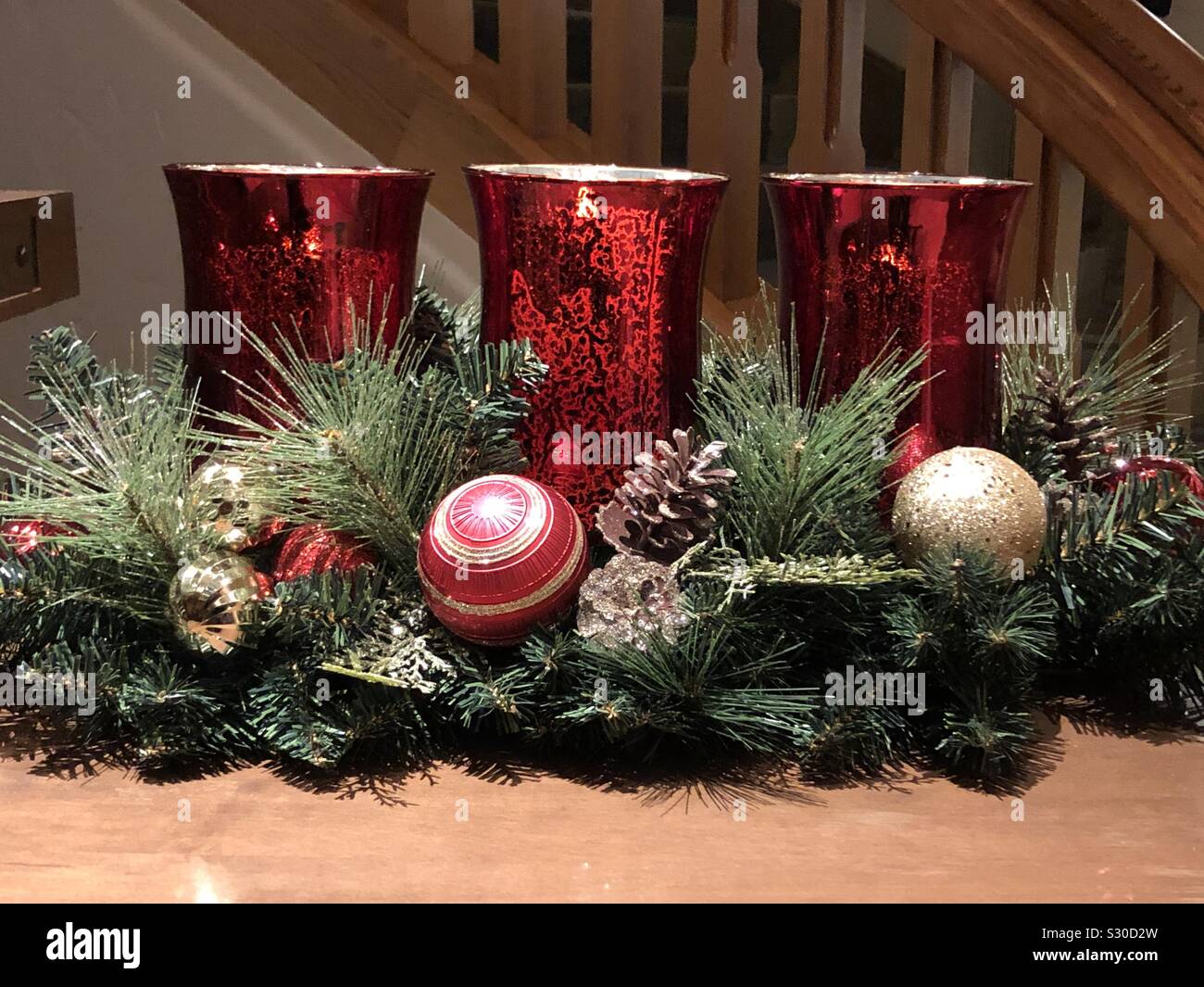 Vetro rosso portacandele con vegetazione pigne e glittery ornamenti a sfera Foto Stock