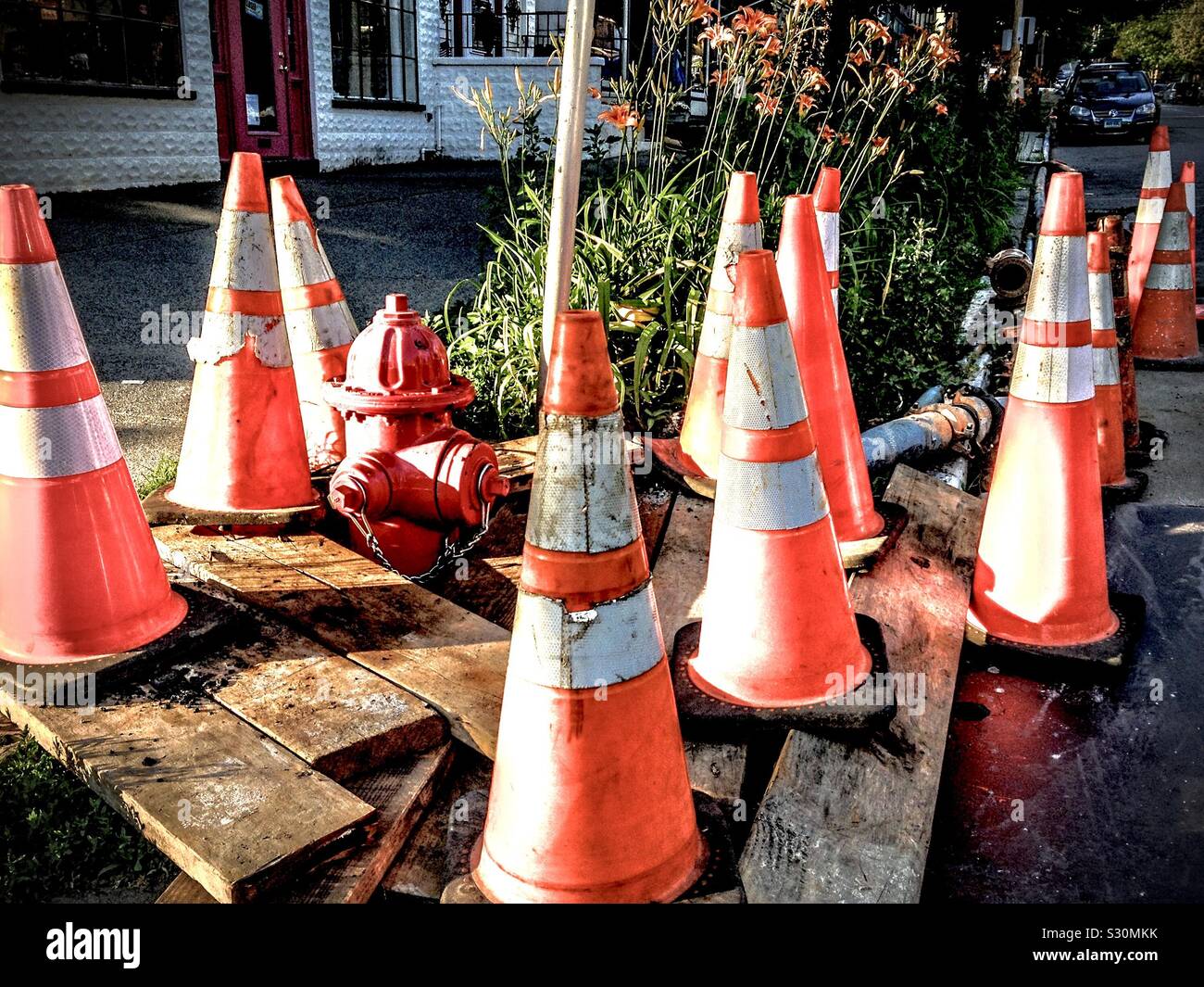 I coni riflettenti di plastica arancione del traffico intorno ad un idrante di fuoco danneggiato in una piccola città nella valle di Hudson, New York, Stati Uniti. 2013 Foto Stock