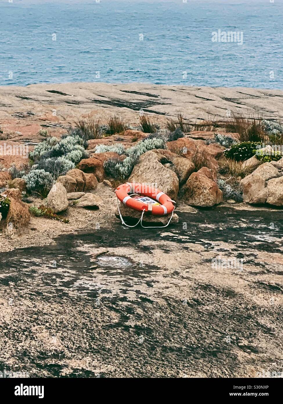 Orange salvagente anello su rocce di Cape Leeuwin, Western Australia. Novembre 2019. Dove l'Oceano Indiano incontra l'Oceano del Sud. Foto Stock