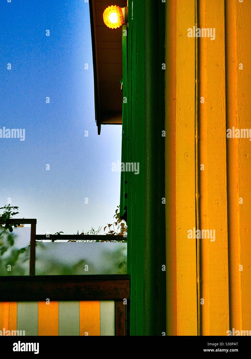 Accesa la lampadina fuori dipinte di giallo e verde cabina di legname, Svezia Foto Stock