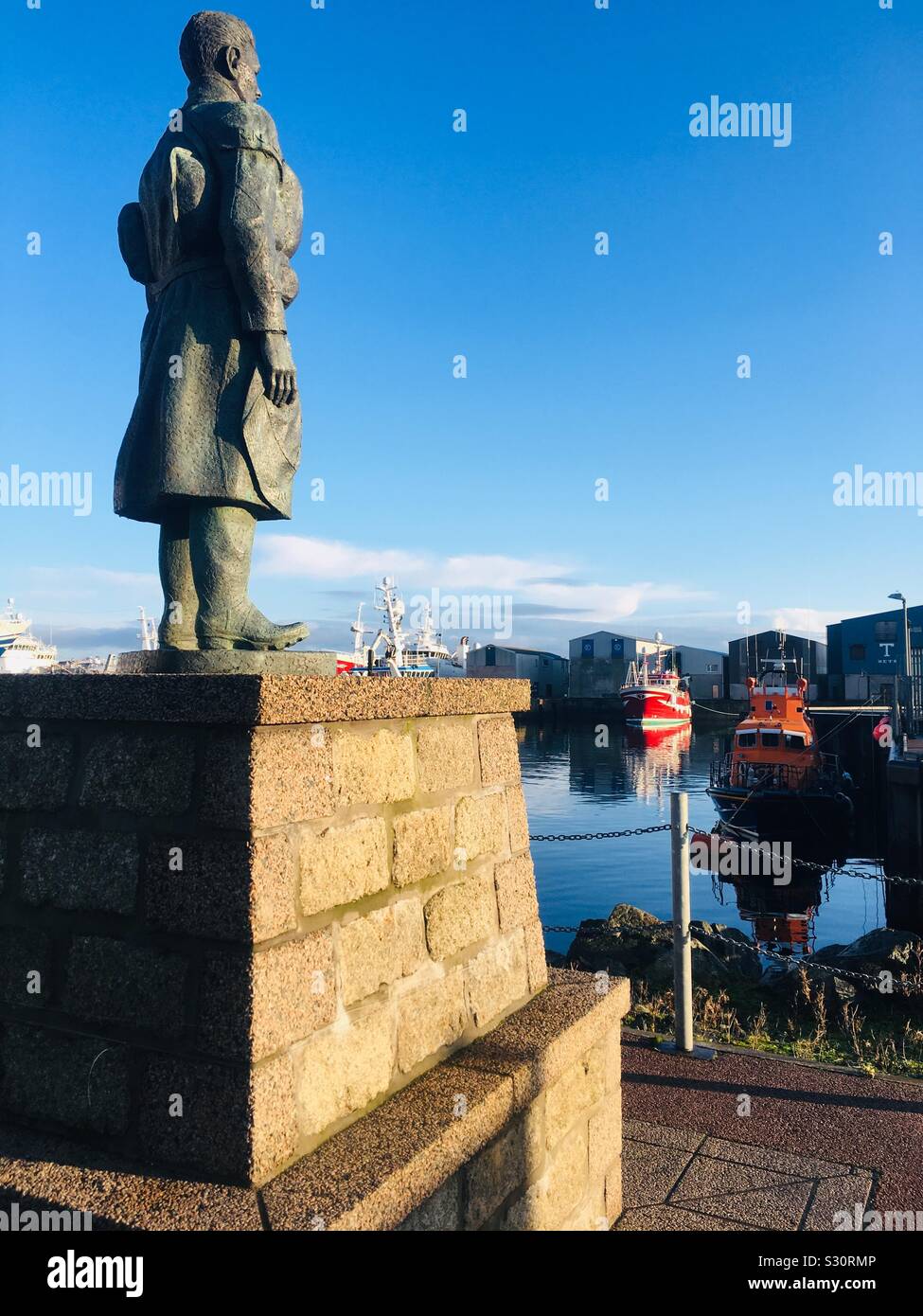 RNLI Memorial statua, Fraserburgh, guardando verso la scialuppa di salvataggio nel porto Foto Stock