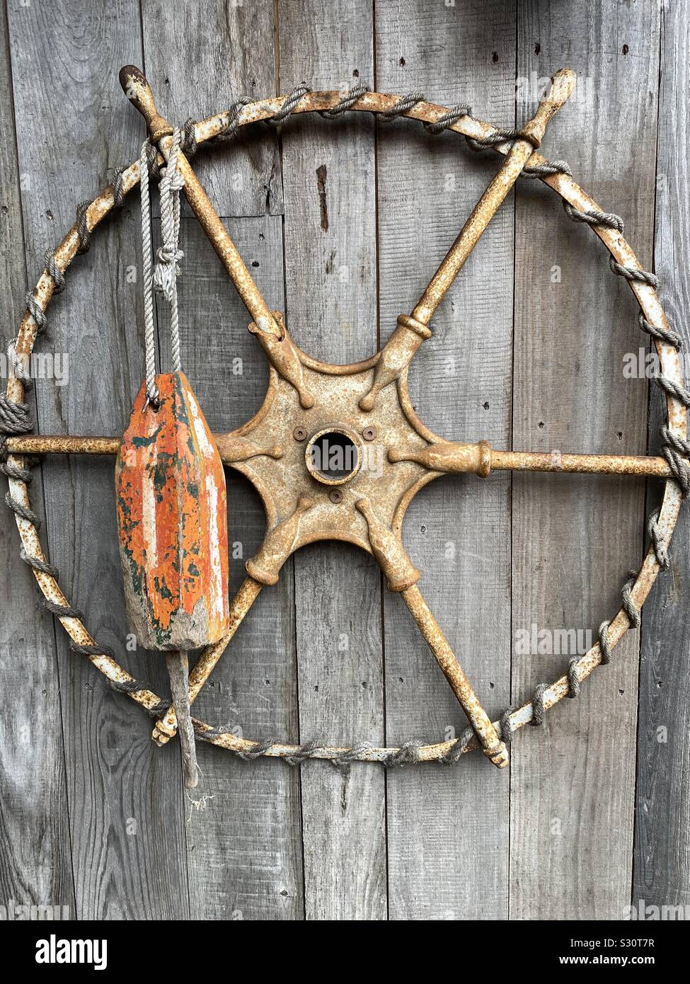 Capitano ruota e ancoraggio in barca su un sfondo di legno Foto Stock