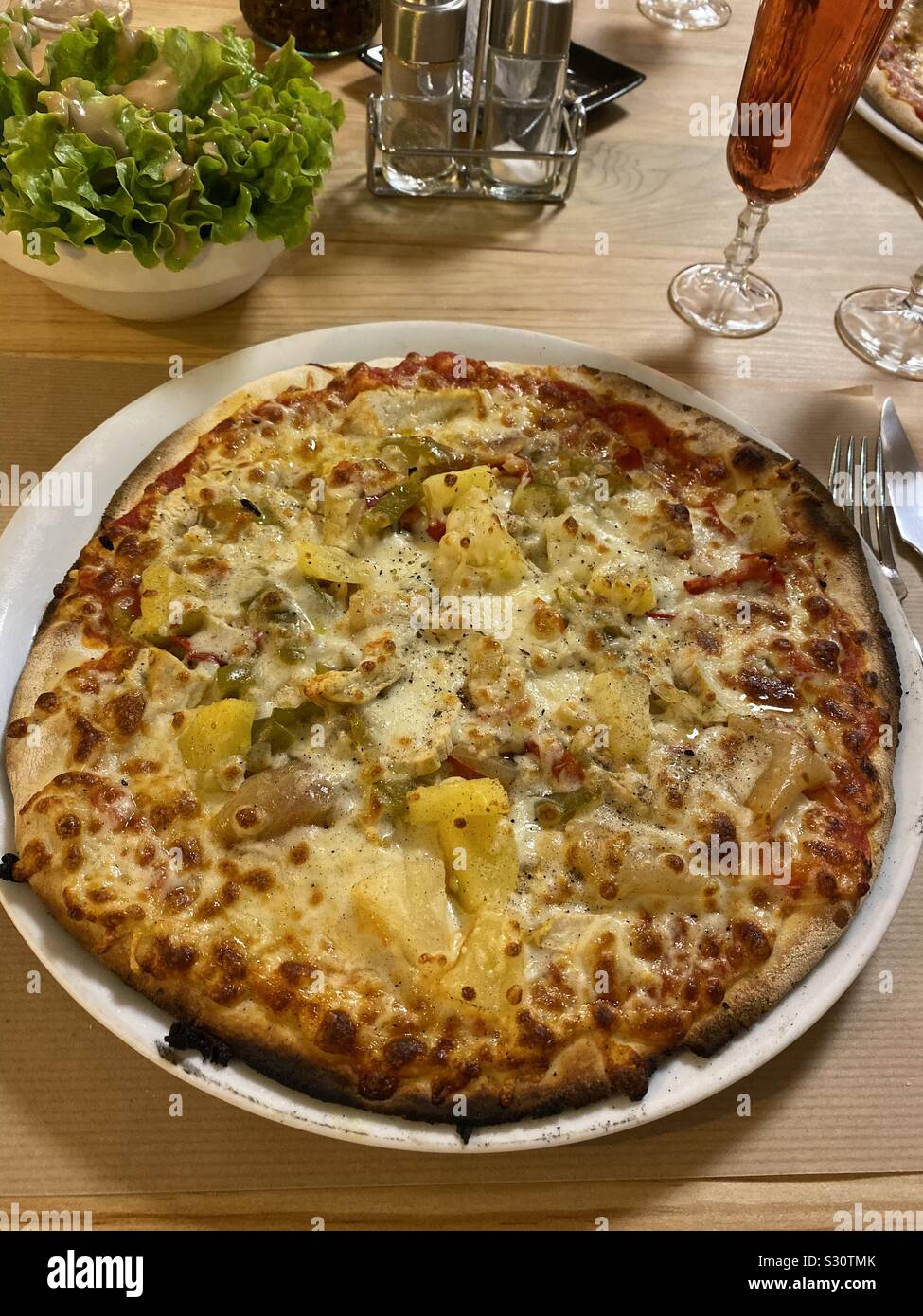 Pollo e ananas Pizza in un ristorante con insalata e vino - Immagine stock catturata con smartphone