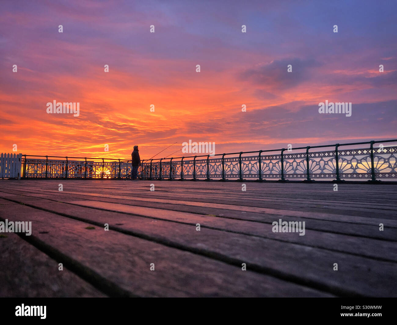 Pescatore solitario all alba Penarth pier, Dicembre. Foto Stock