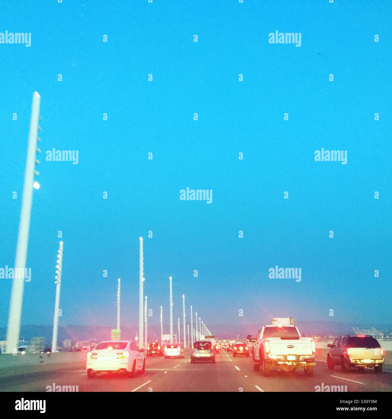 Traffico dell'ora di punta sul Bay Bridge, luci di coda rosse all'ora magica. Le auto vanno da San Francisco a Oakland. Spostamenti serali nella zona della baia. - Immagine stock catturata con smartphone