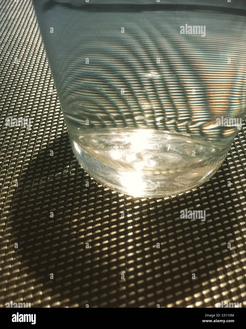 Bicchiere di acqua con rifrangere la luce del sole e il contrasto tra sfondo grafico. Foto Stock