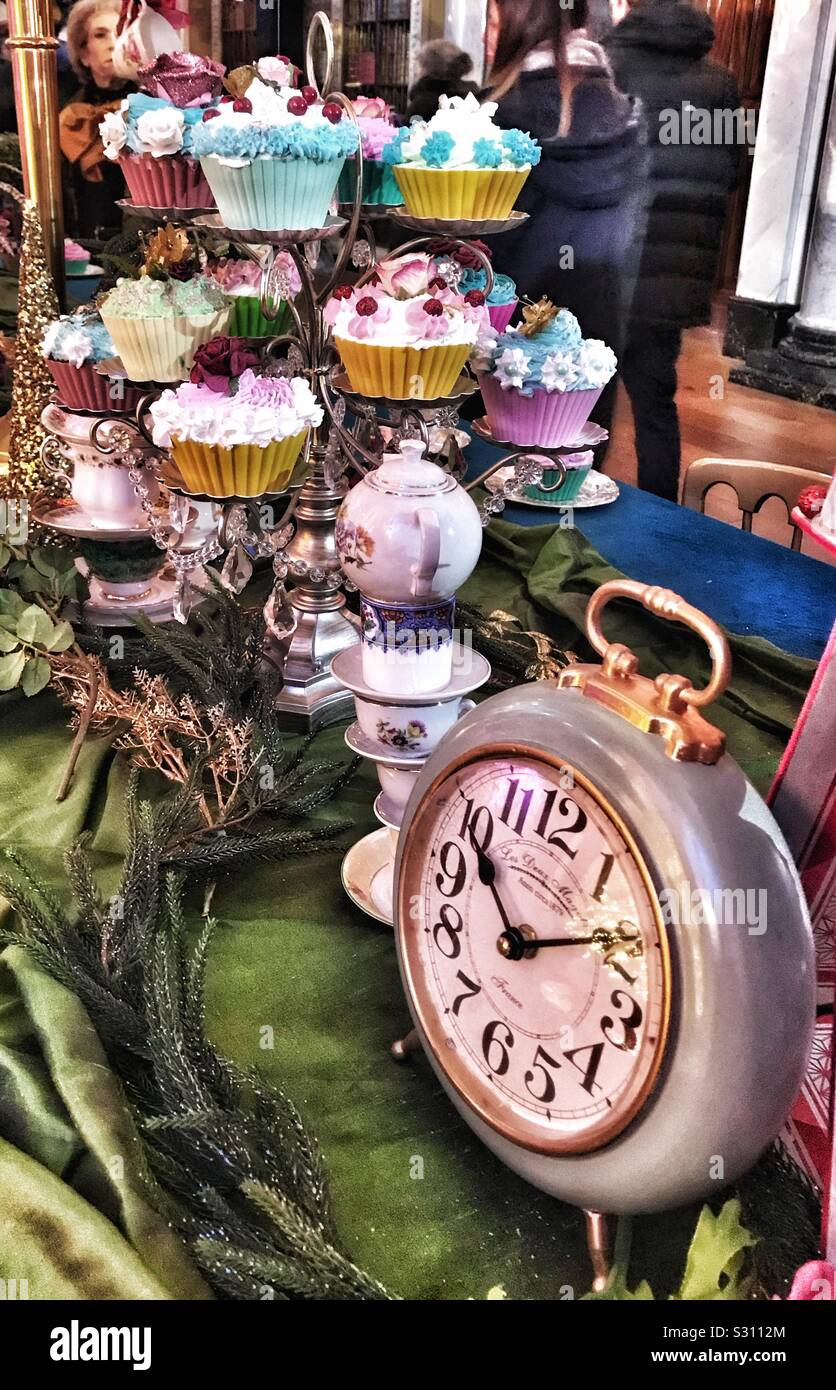 Alice nel Palazzo di Blenheim Palace il Natale 2019 - Mad Hatters Tea Party tabella con uno stand di tortine su di esso e un orologio. Foto Stock