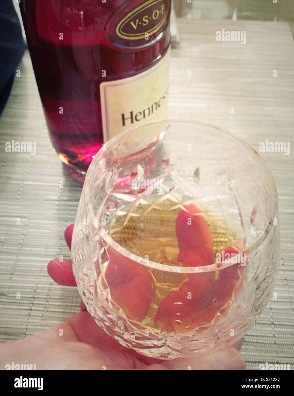 Primo piano di un nifter cristallino di Hennessey cognac tenuto da un uomo Foto Stock
