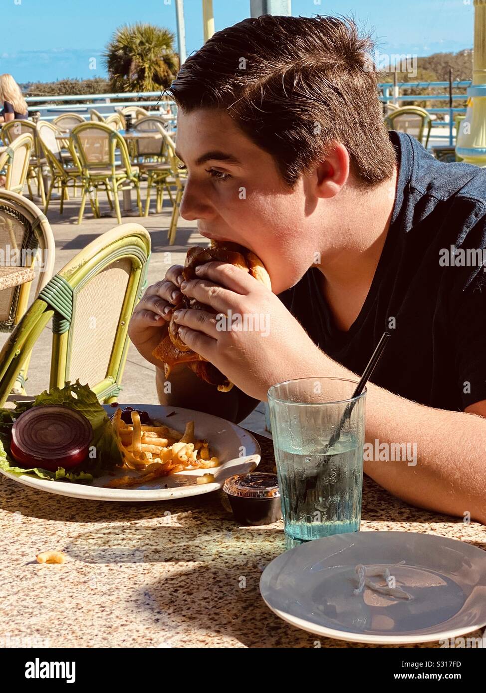 Ragazzo di mangiare un enorme cheeseburger Foto Stock