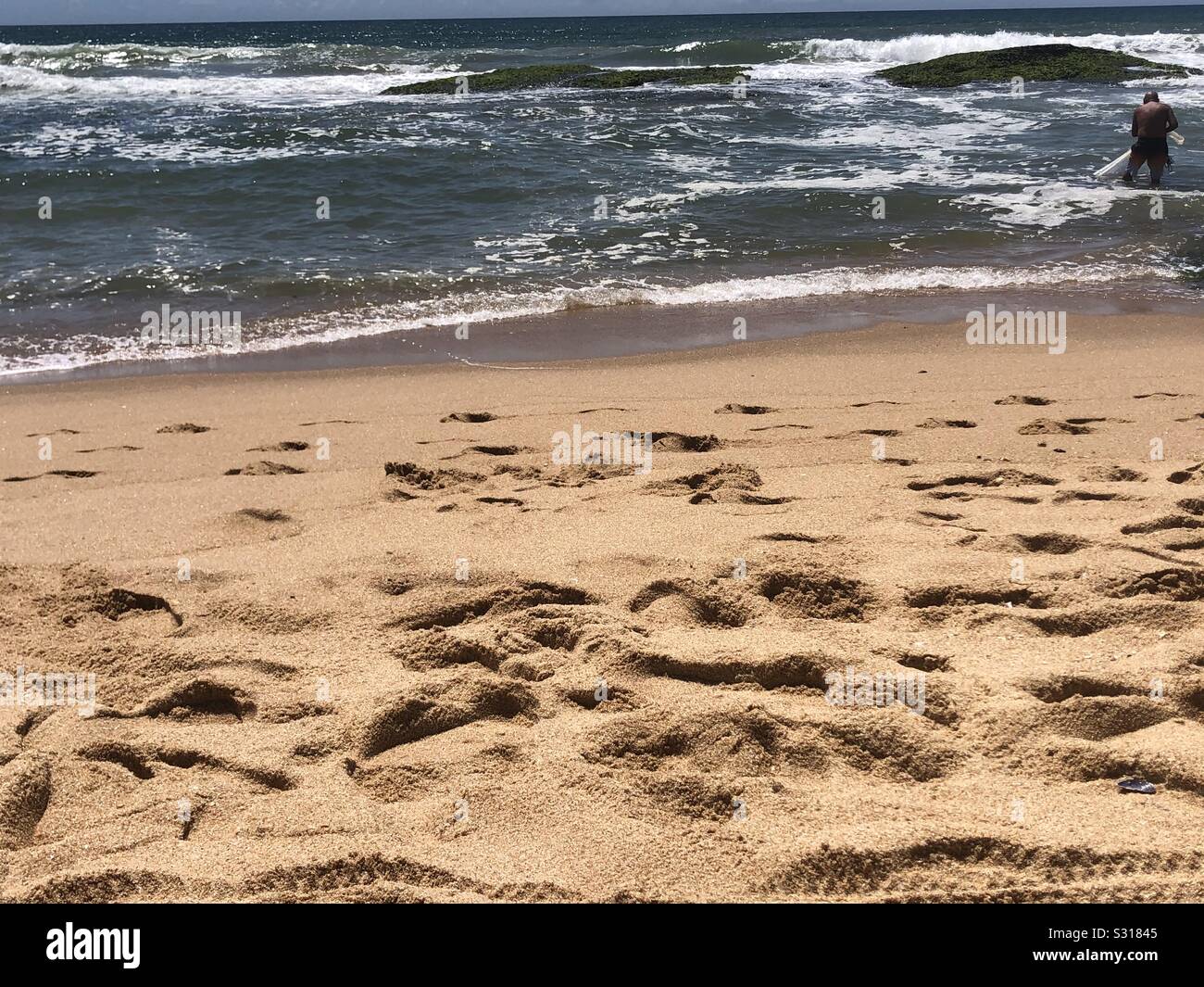 Pescatore solitario veli il suo commercio da un ben viaggiato beach Foto Stock