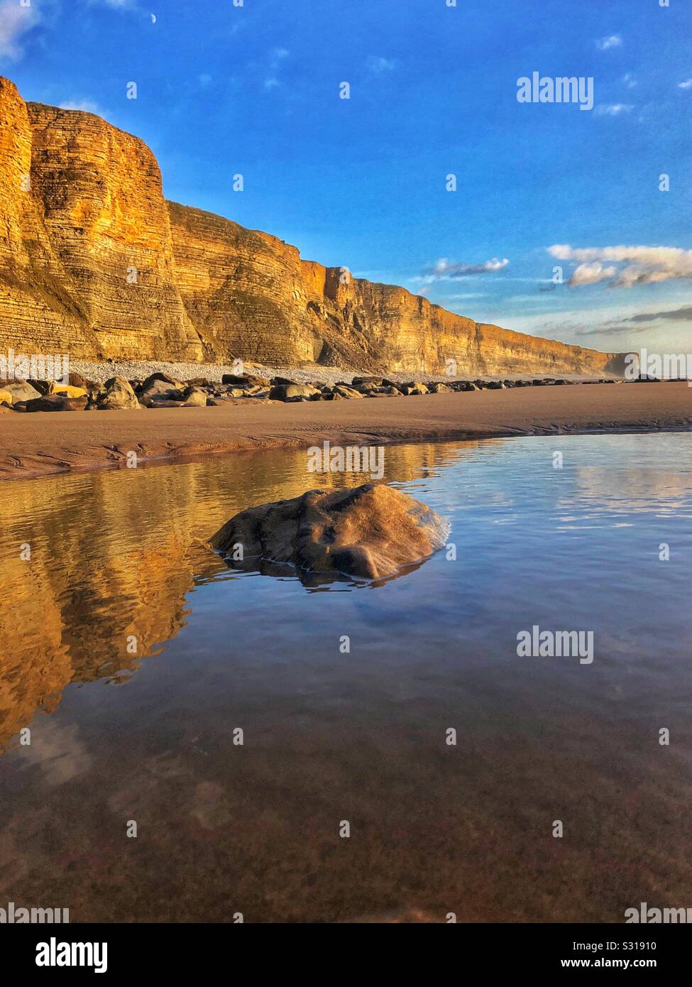 Scogliere illuminate dal sole riflessa nella sabbia bagnata, Glamorgan heritage costa, Traeth Mawr, South Wales, gennaio. Foto Stock