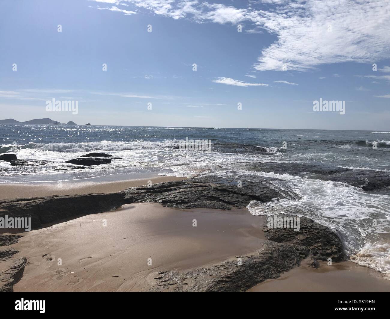 La Santana è fornisce un lontano da sfondo alla marea in uscita sulla spiaggia di Cavaleiros, RJ, Brasile Foto Stock