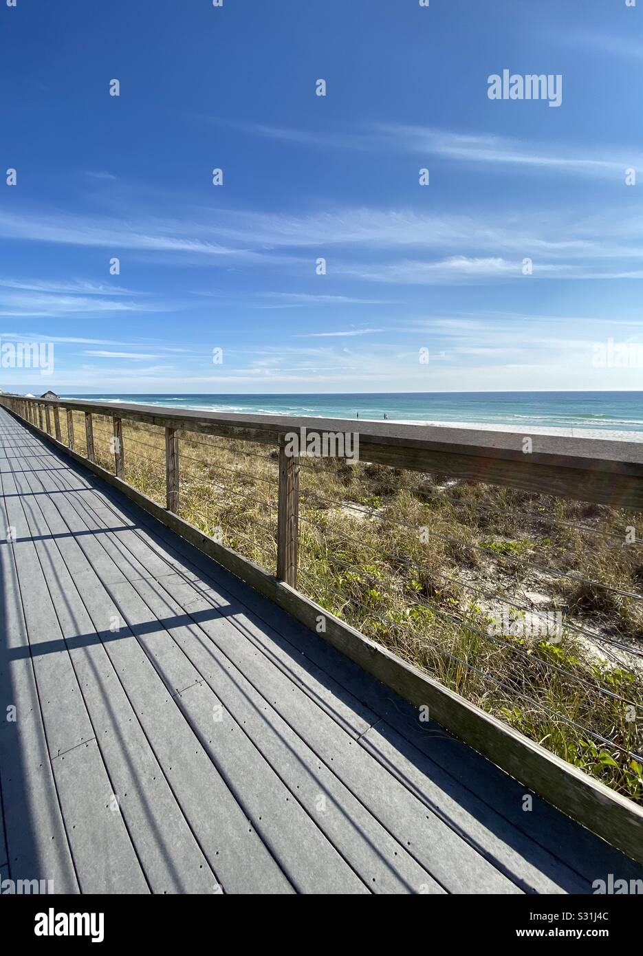 Lungo passaggio pedonale sulla spiaggia con vista dell'acqua smeraldo e dei bellissimi cieli blu Foto Stock