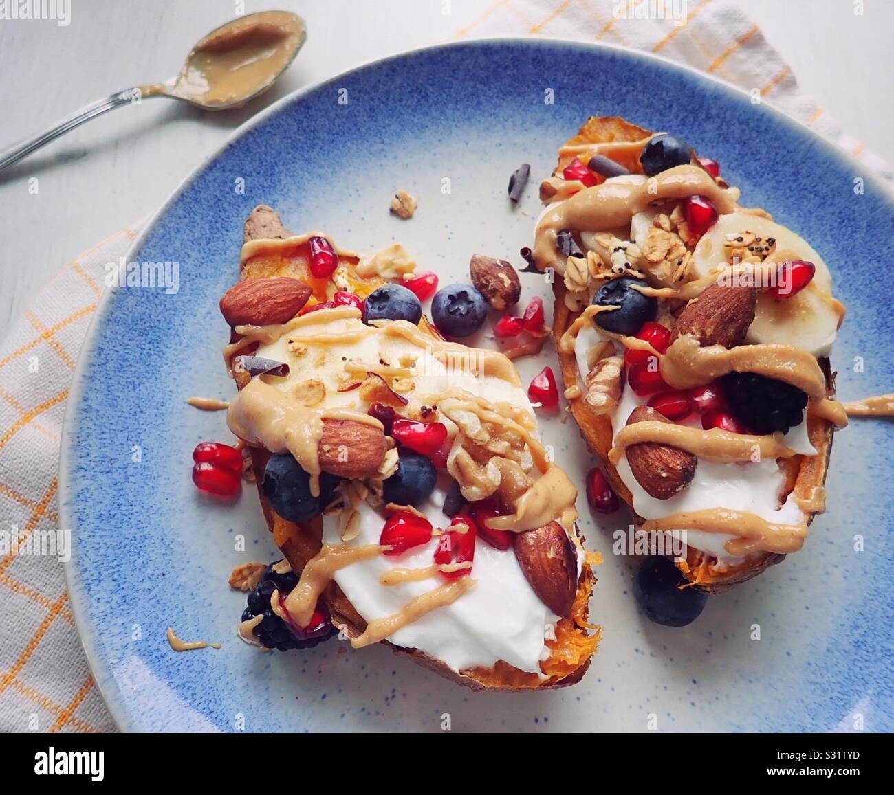 Patate dolci al forno con yogurt, muesli e burro di arachidi. Perfetto sana colazione! Foto Stock