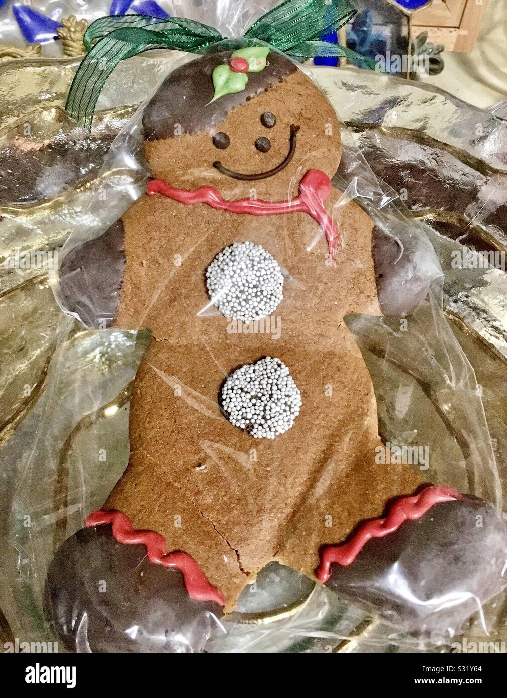 Gingerbread uomo o donna con cioccolato immerso le mani e i piedi, candy pulsanti e nastro verde sorridente in un sacchetto di cellophane - Immagine stock catturata con smartphone