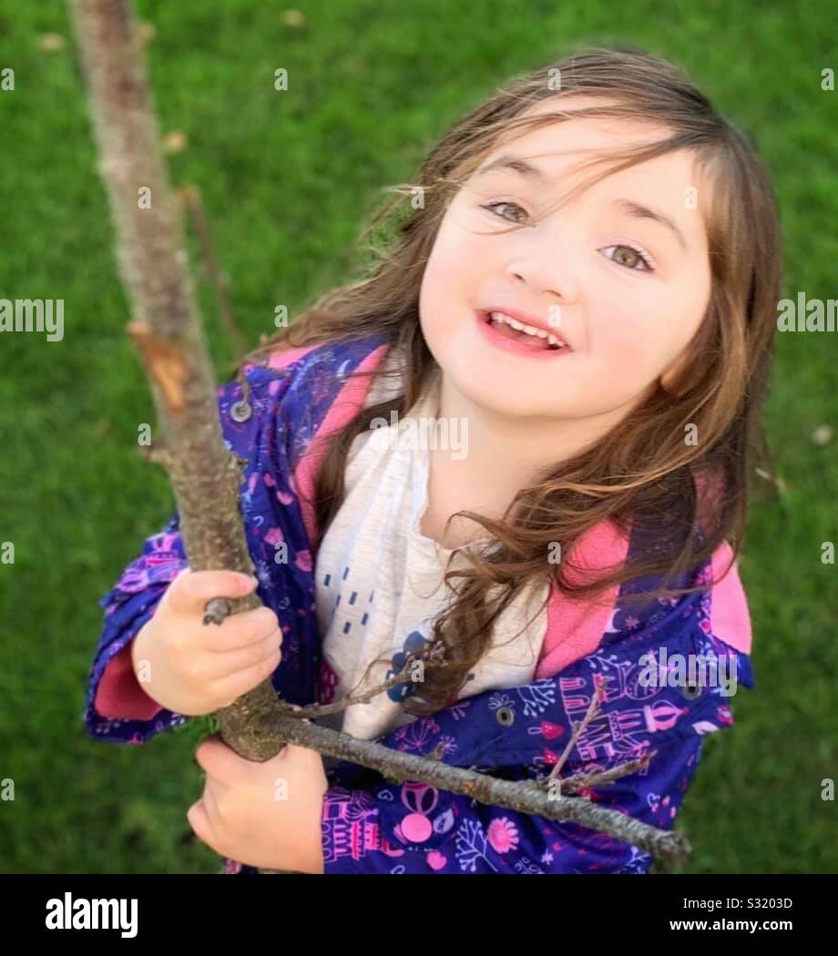 Ragazza nuda di contenimento ramo di albero pendente ritornare sorridente Foto Stock
