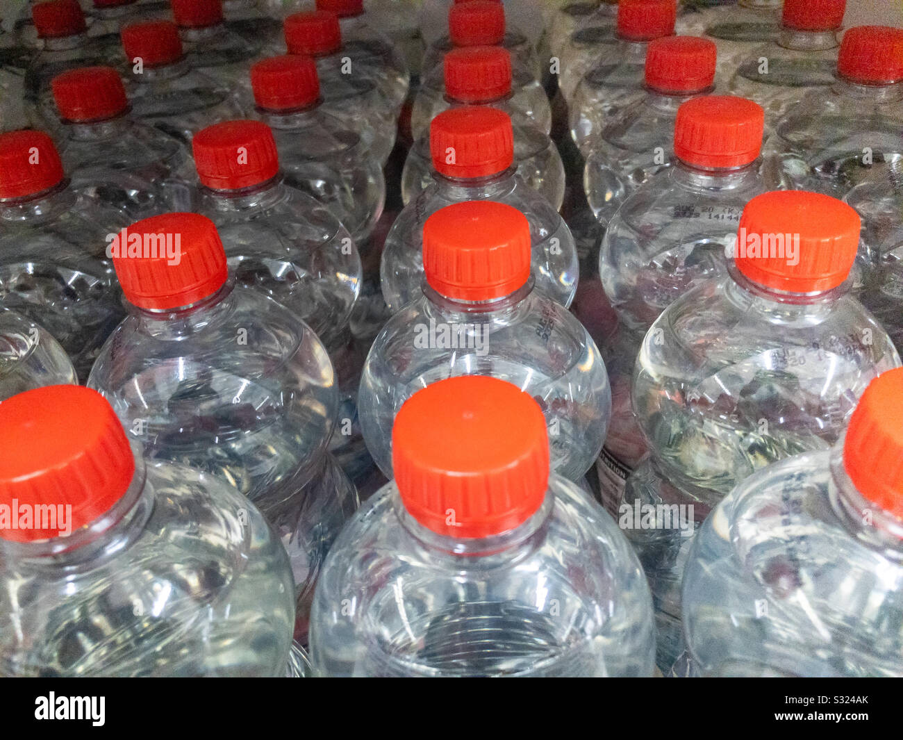 File di bottiglie d'acqua di plastica su un ripiano del supermercato. Foto Stock