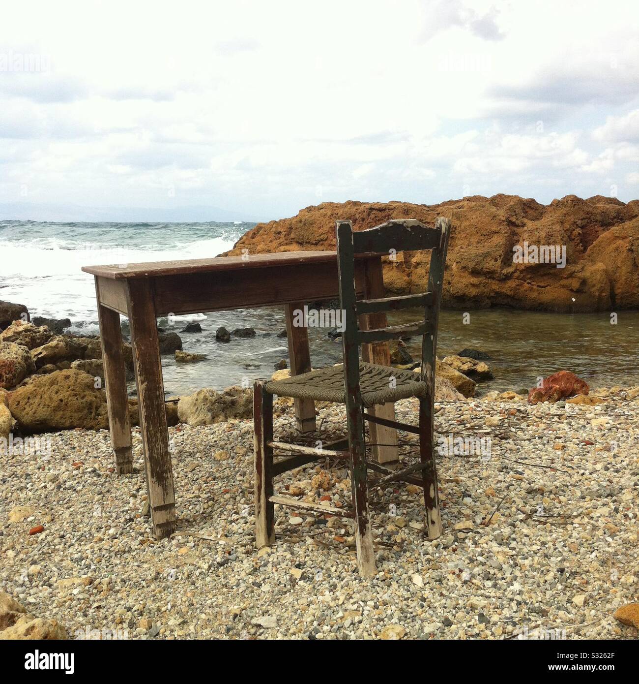 Sedia solitaria vecchia e la tavola sulla riva del mare a Chania Creta Foto Stock