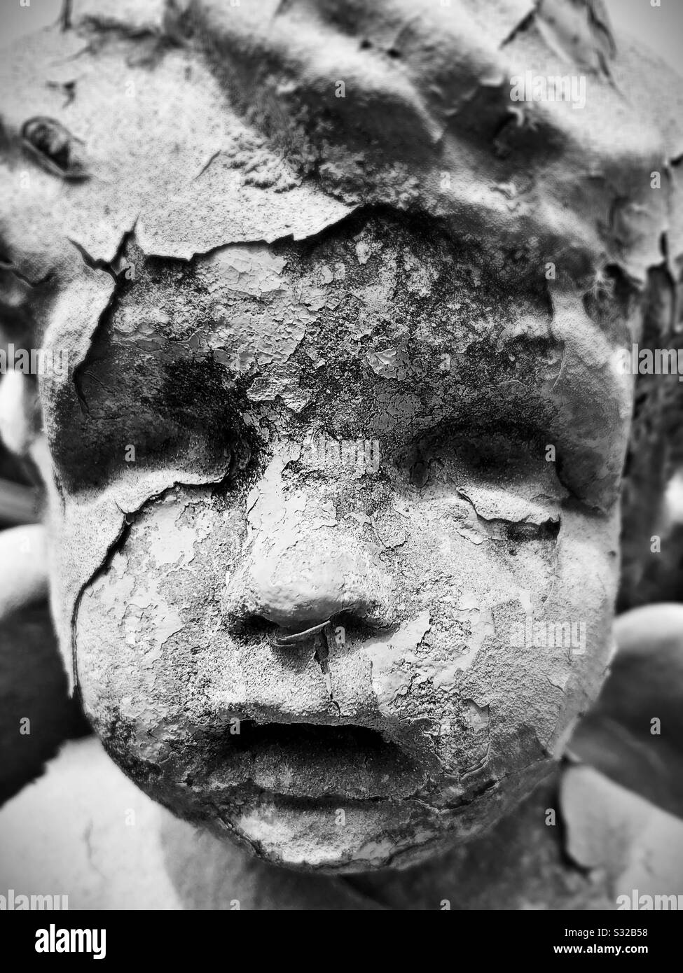 Una vecchia statua di un bambino scricchiolata e creepy decadente. Foto Stock