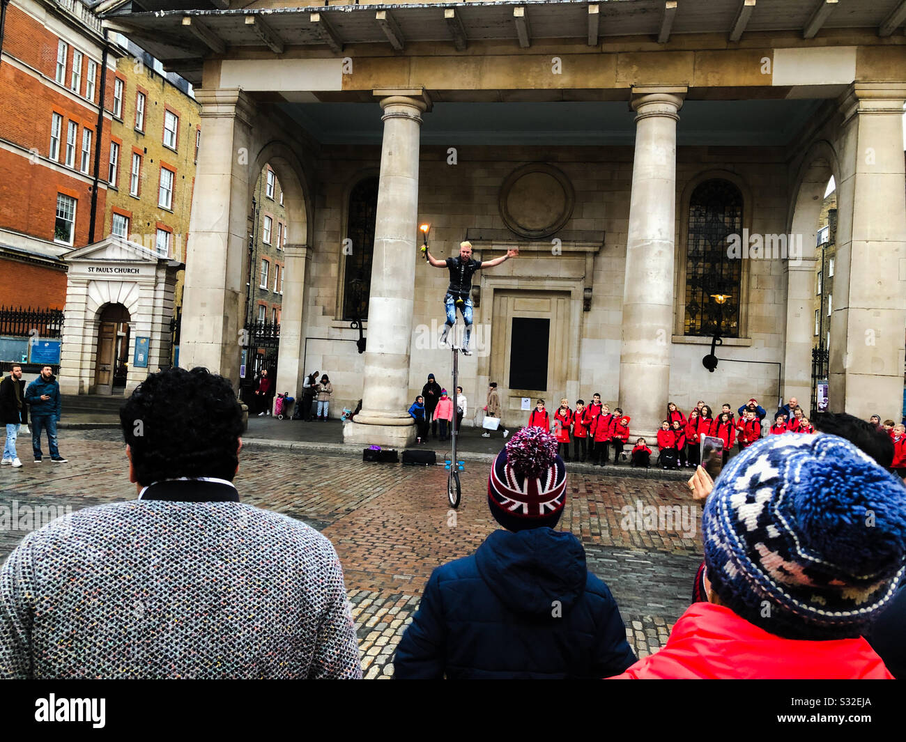 I turisti che guardano una strada in un monociclo fuori la chiesa di St Paul, Covent Garden, Londra, Inghilterra - Immagine stock catturata con smartphone