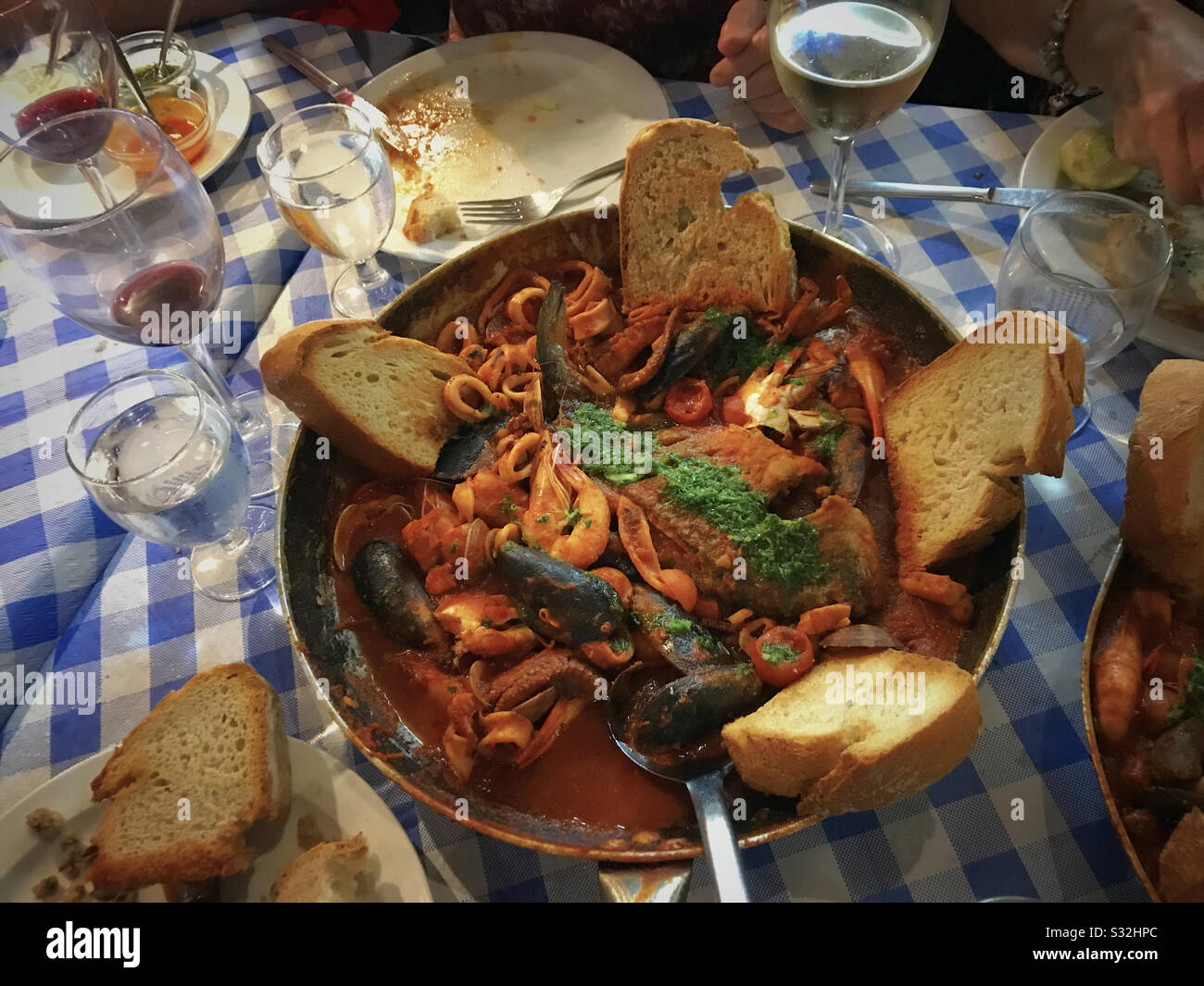 Cazuela pesce e frutti di mare stufato con pane su tavolo a scacchi Foto Stock