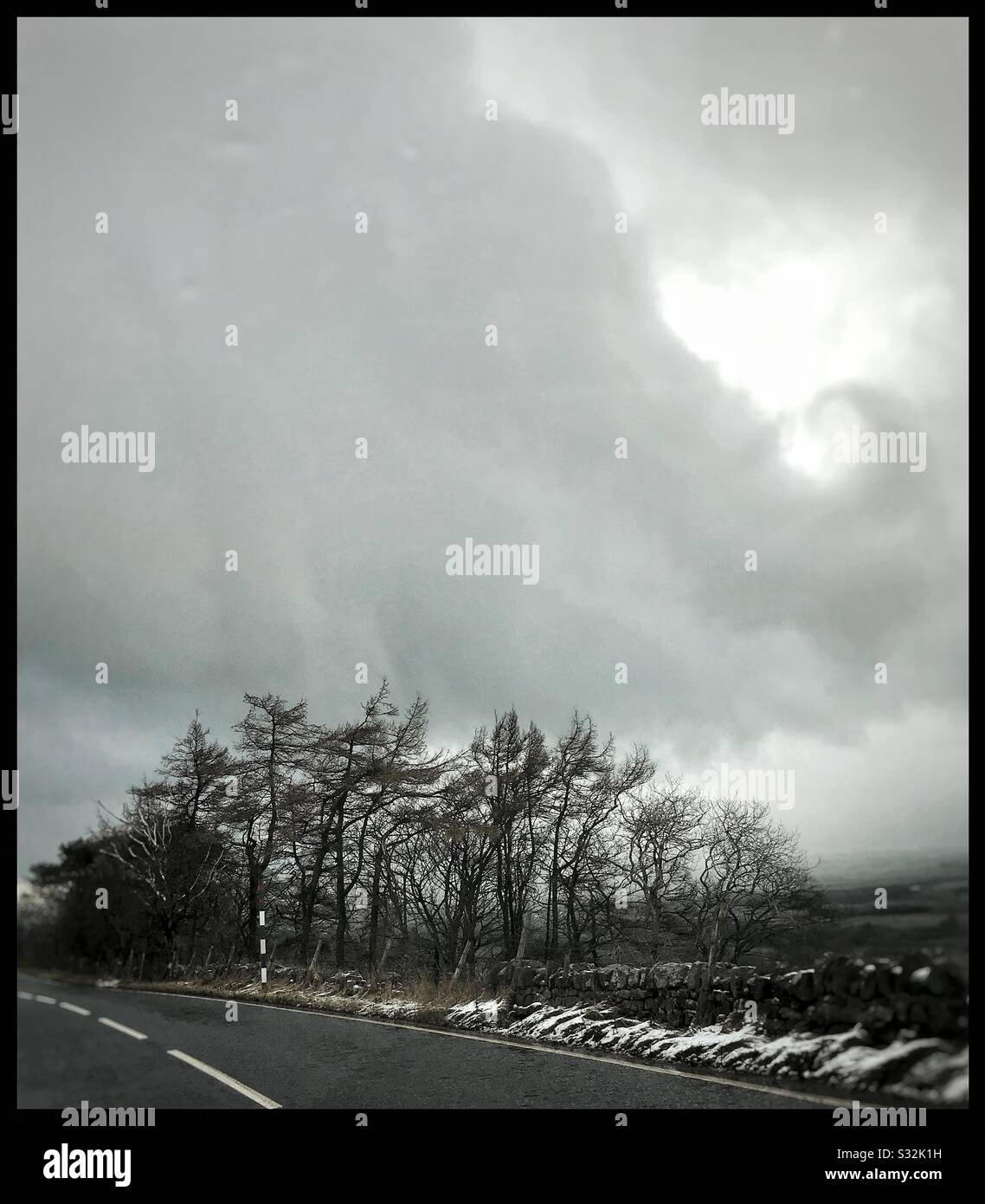 Nube di neve invernale con bordi curling sopra gli alberi vicino a una strada Foto Stock