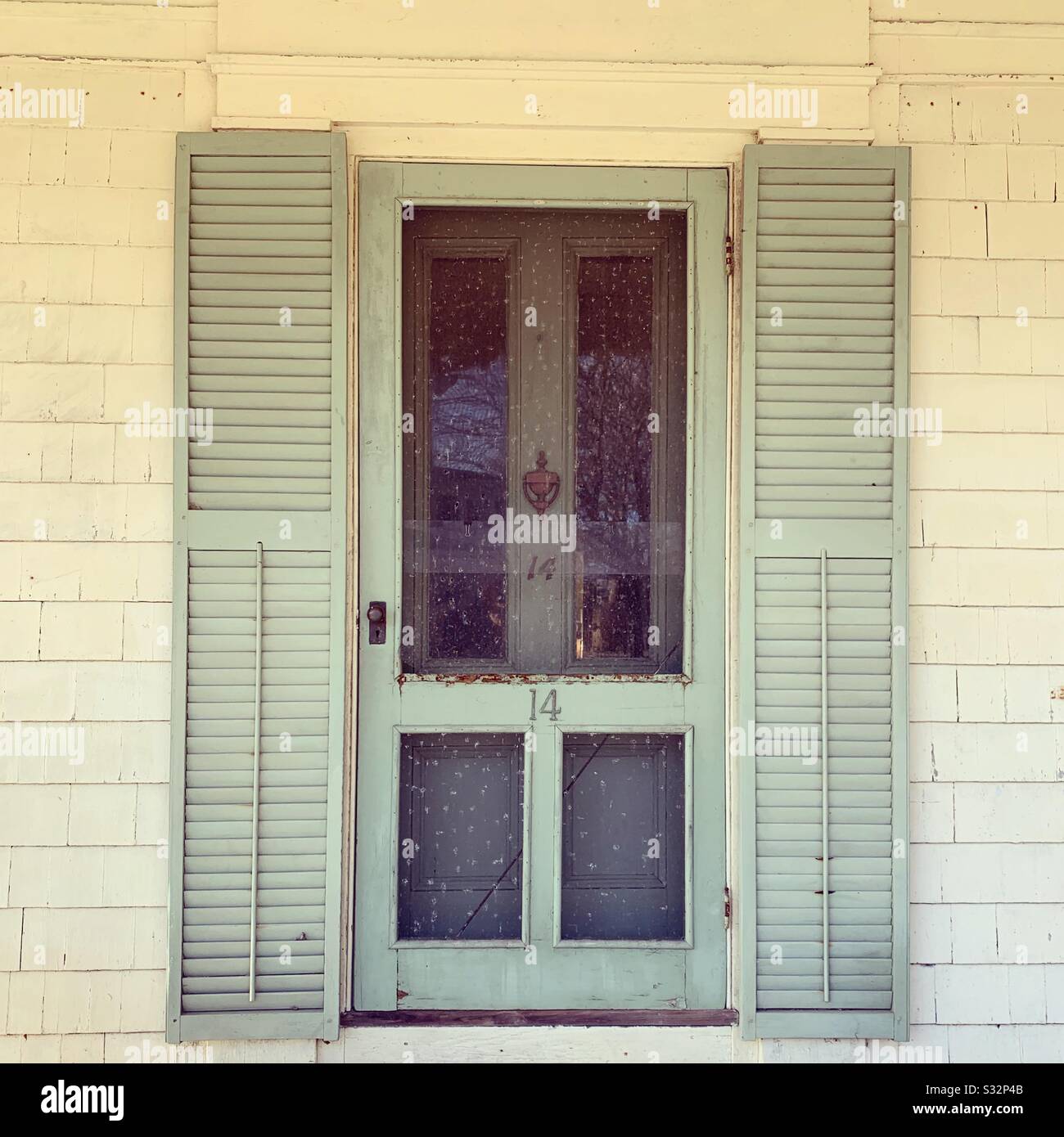 Persiane bianche porta anteriore vecchia sedia a dondolo su una vecchia casa a Woods Hole, Falmouth, Cape Cod, Massachusetts, Stati Uniti - Immagine stock catturata con smartphone