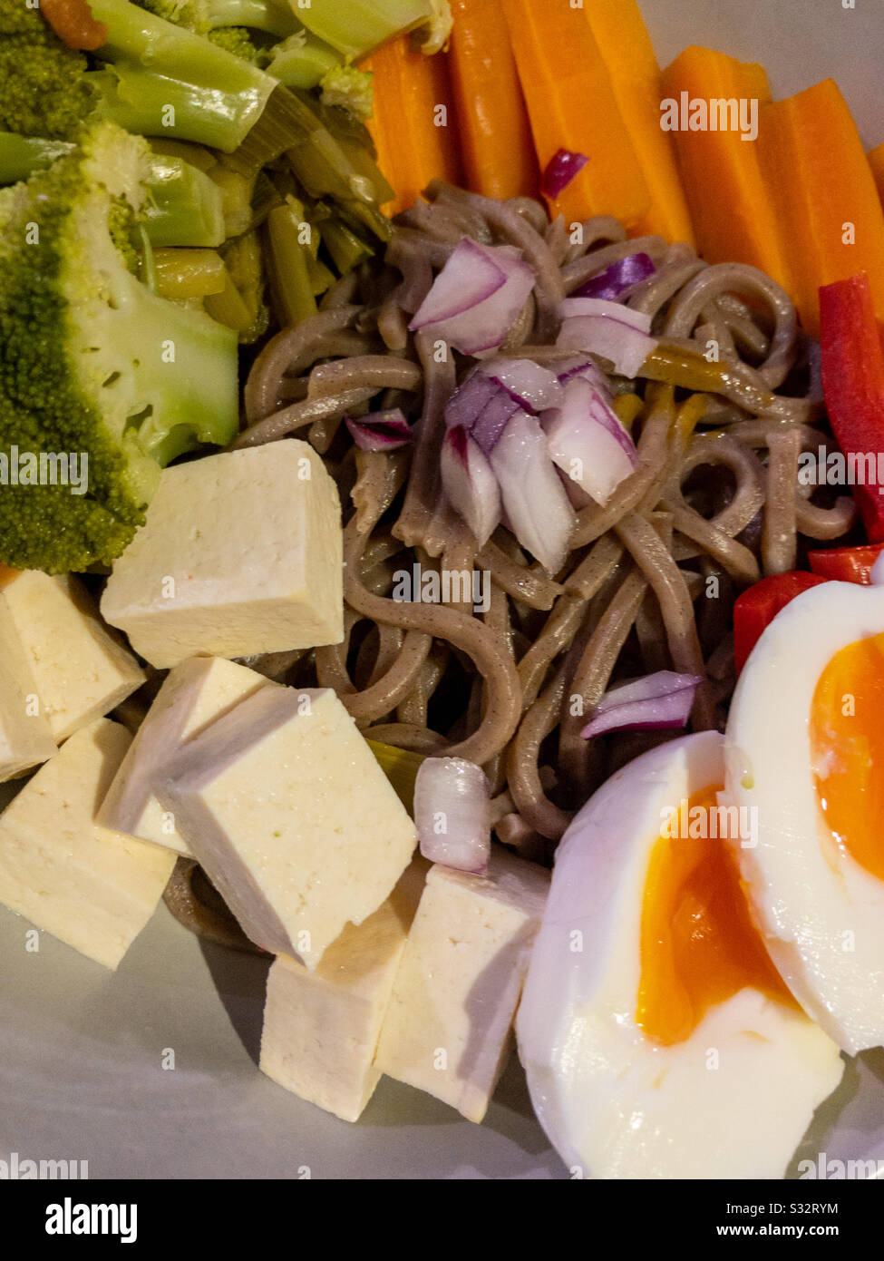 Tagliatelle di soba giapponesi con tofu, broccoli, carote, cipolle e uova sode. - Immagine stock catturata con smartphone