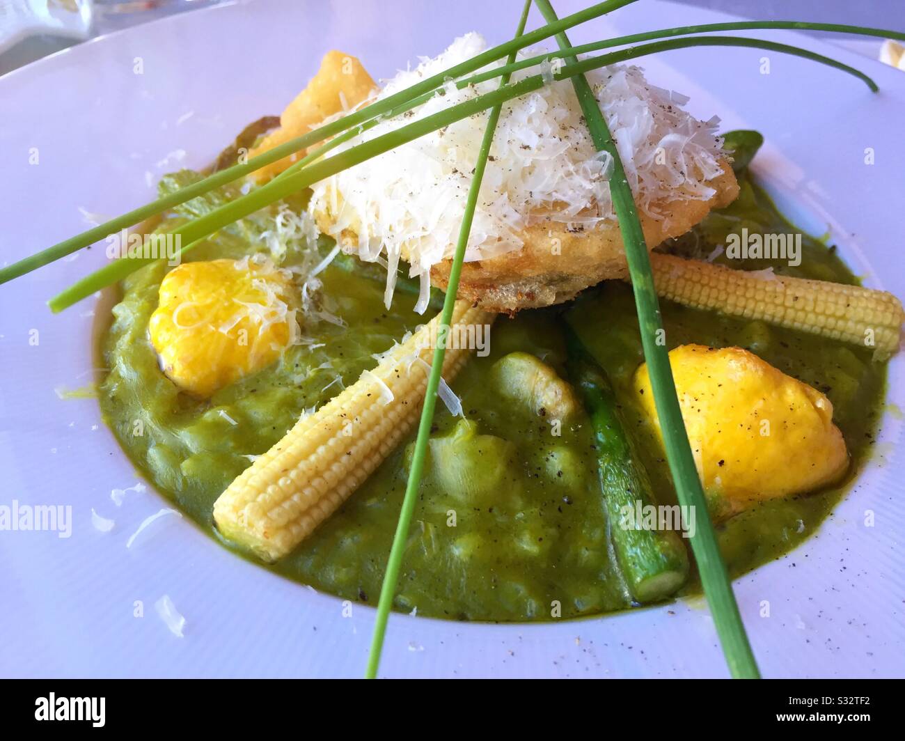 Entrée gourmet di risotti di asparagi verdi serviti con mais, zucca patty pan, fiori di zucca e erba cipollina, Stati Uniti Foto Stock