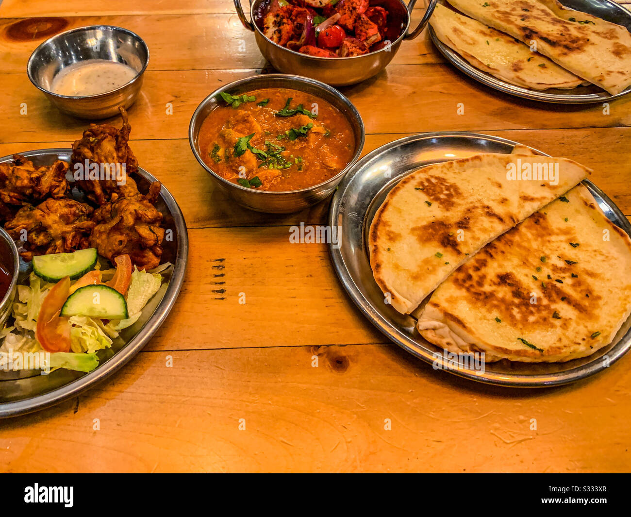 Selezione di cibo indiano ristorante in ciotole tra cui pollo tikka masala naan pane riso e patatine fritte Foto Stock