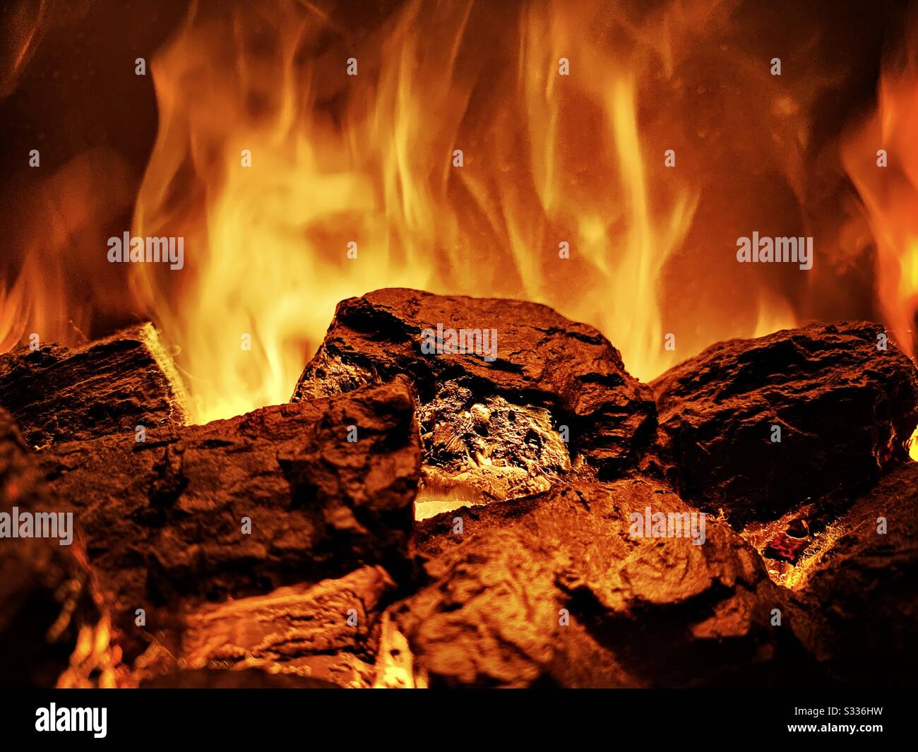 Vista ravvicinata dei carboni caldi su un fuoco acceso in casa. Caminetto con un caldo bagliore arancione e fiamme. Copiare lo spazio in alto Foto Stock