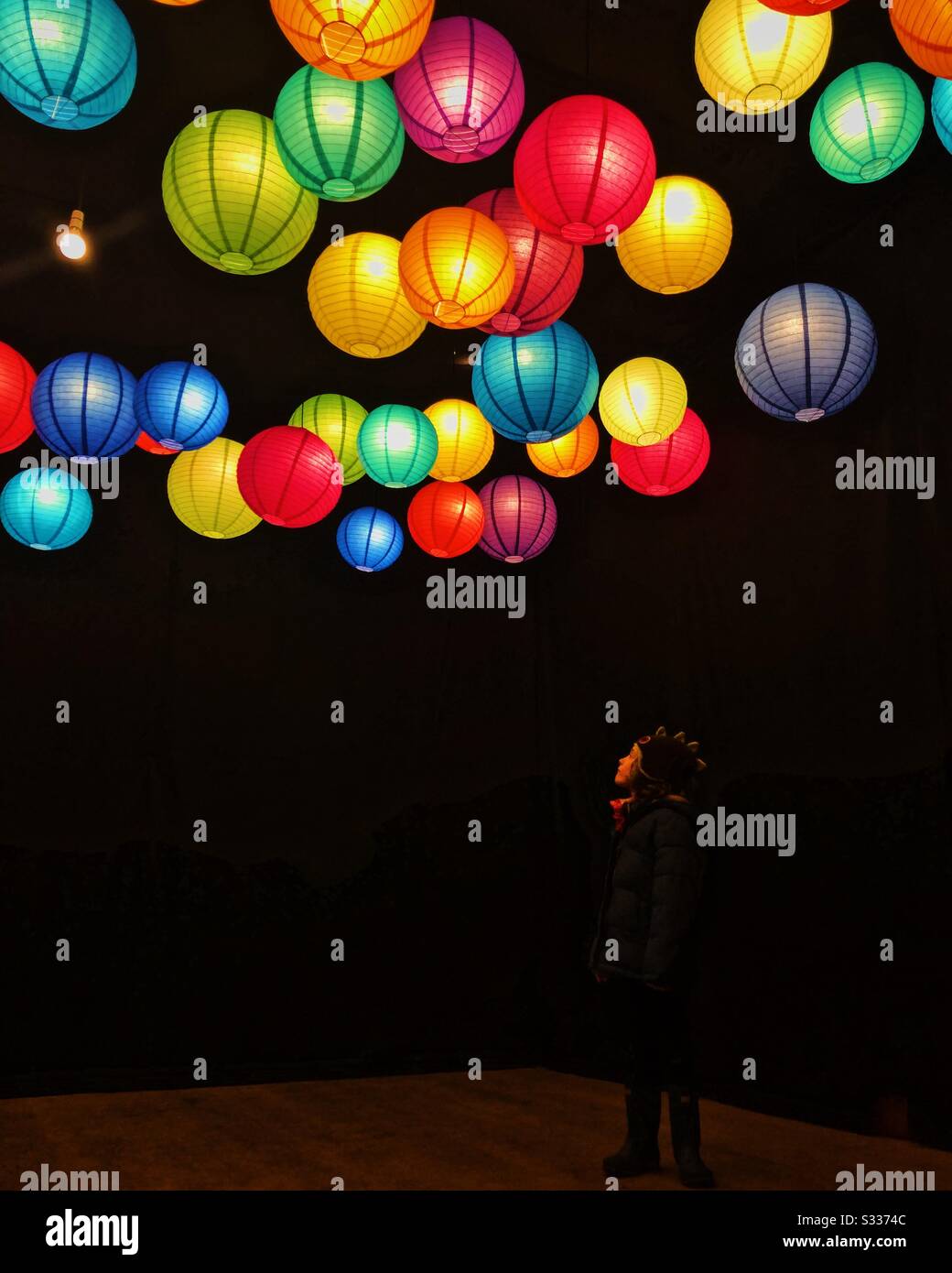 Ragazzo che guarda in alto le luci colorate lanterna. Foto Stock