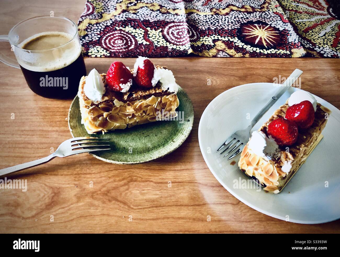 Due pezzi di torta napoleone e una tazza di caffè nero su un tavolo di legno Foto Stock