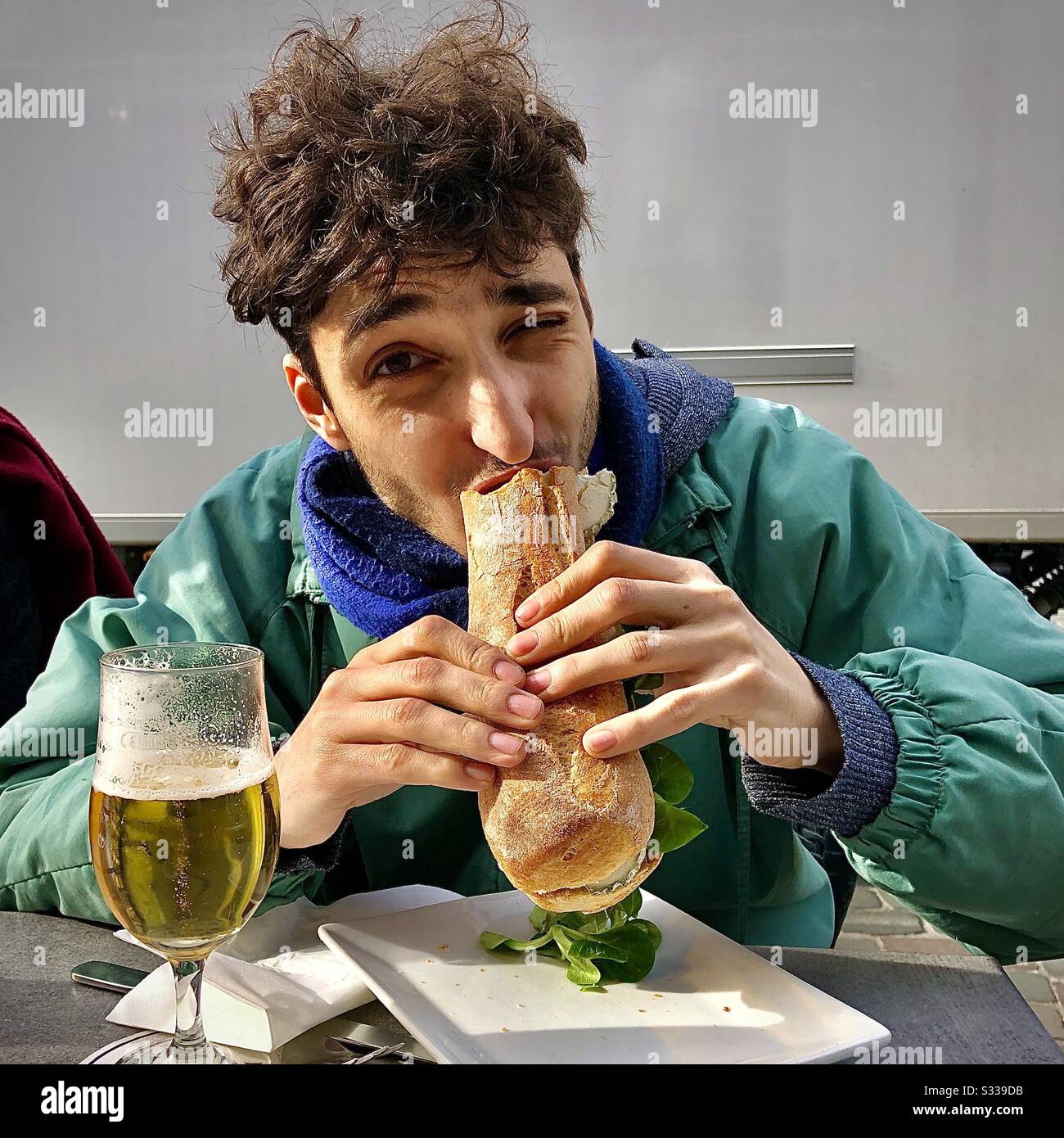 Giovane uomo che mangia un panino di baguette appena fatto. - Immagine stock catturata con smartphone