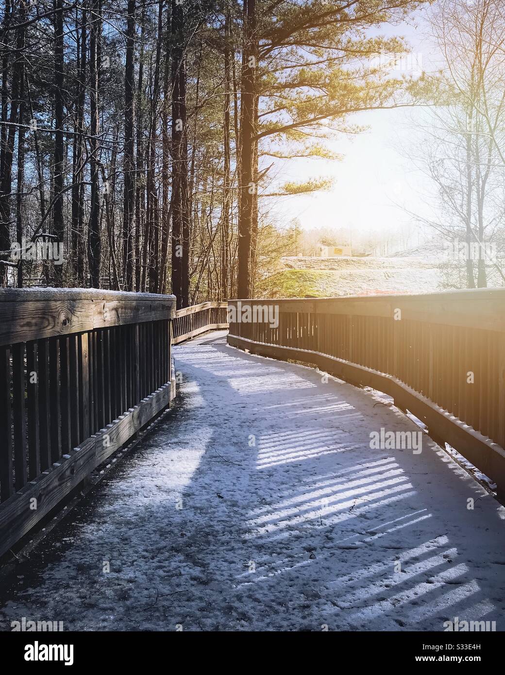 Mattina luce del sole su un ponte di legno con neve Foto Stock