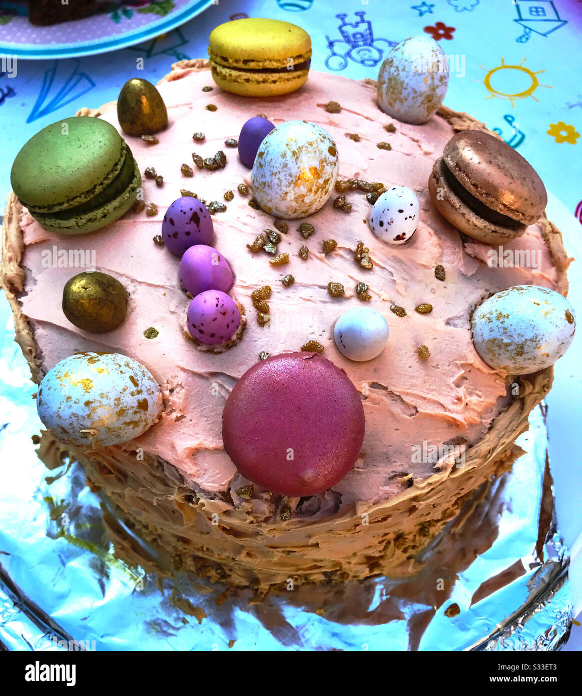Torta di Pasqua decorata con glassa rosa, uova di cioccolato e macaron. - Immagine stock catturata con smartphone