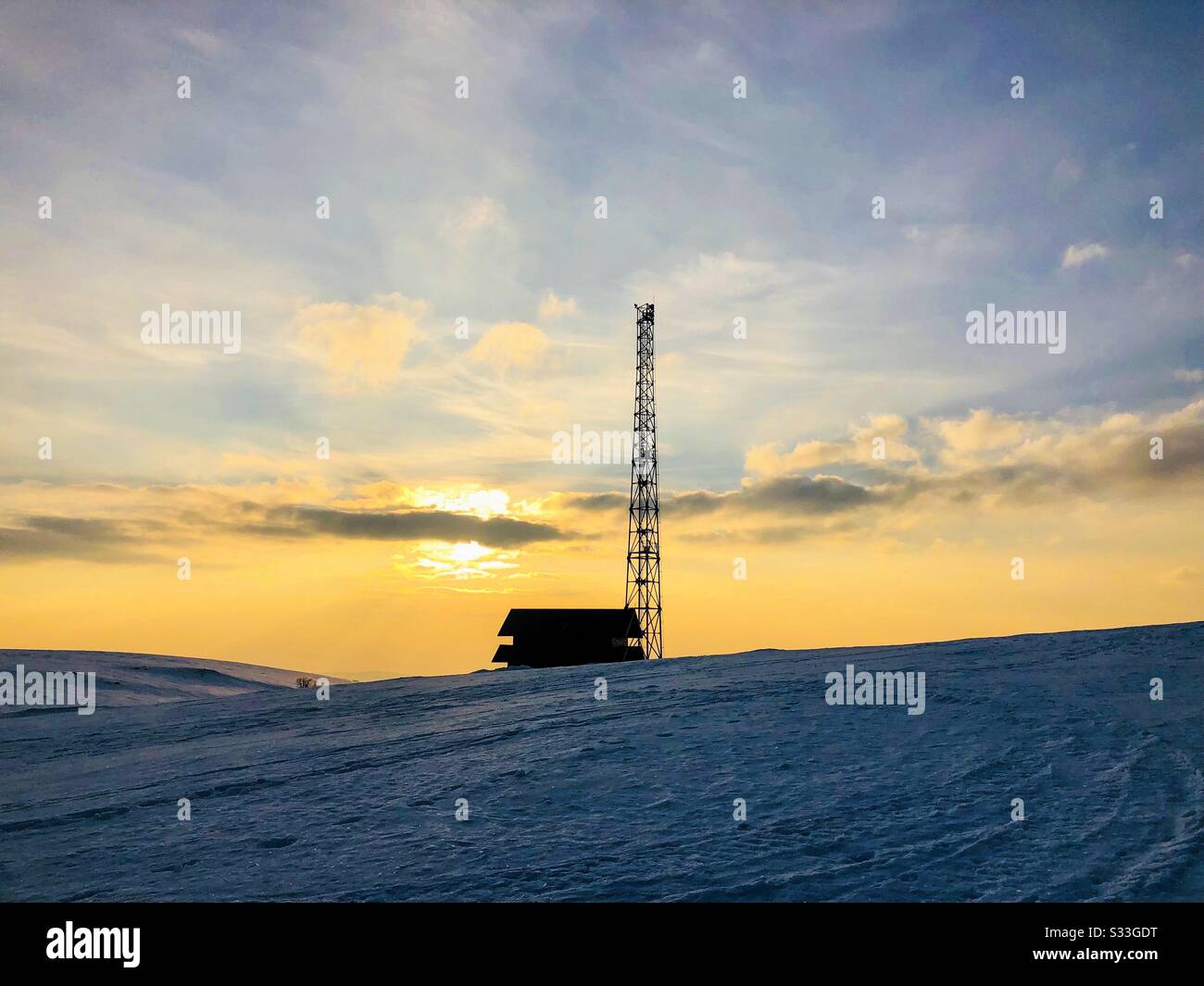 Silhouette di casa e torre di trasmissione al tramonto in inverno Foto Stock