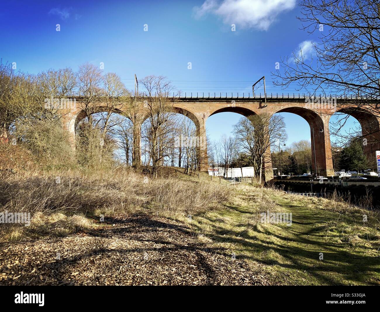 Alti archi rossi formano il viadotto ferroviario Chester Burn con alberi senza foglie durante l'inverno. Imponente architettura ferroviaria del 19th secolo che fa parte della East Coast Mainline Foto Stock