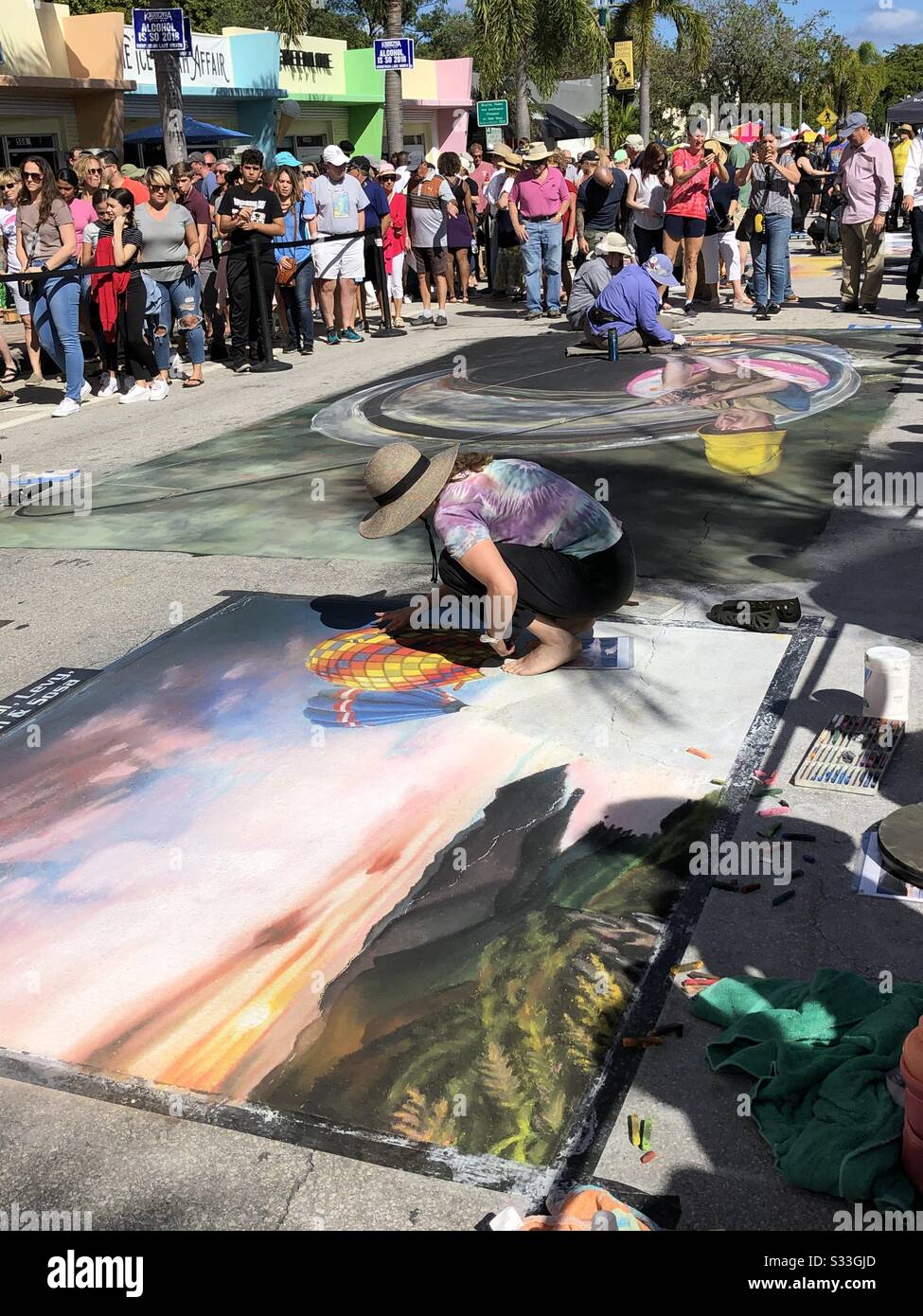 La folla guarda artisti di strada creare murales di gesso marciapiede al Lake Worth Beach Street Painting Festival, Florida, febbraio 2020. Foto Stock