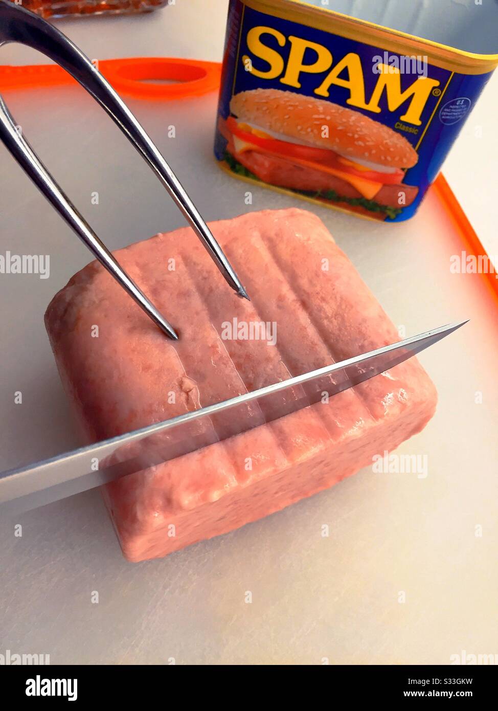 La carne del pranzo dello Spam è intagliata su una tavola da taglio - Immagine stock catturata con smartphone
