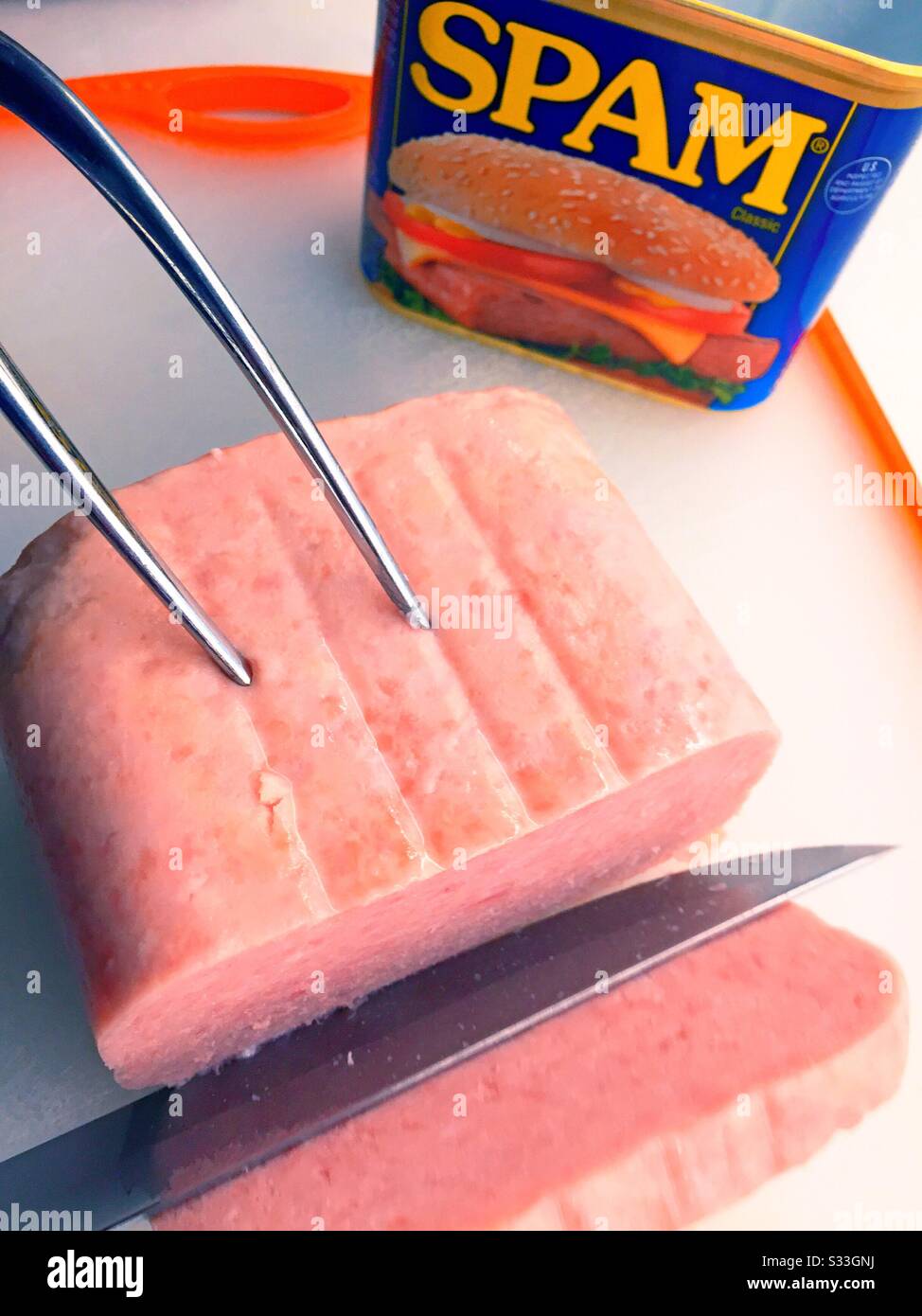 La carne del pranzo dello Spam è intagliata su una tavola da taglio - Immagine stock catturata con smartphone